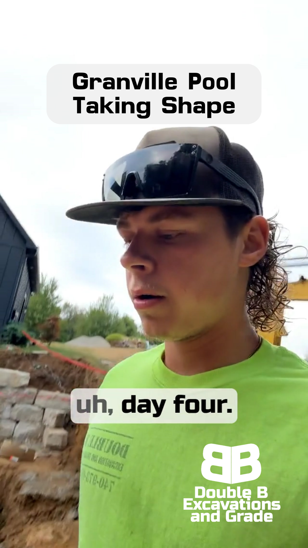 Man in a cap, green shirt, and mullet stands at a construction site. 