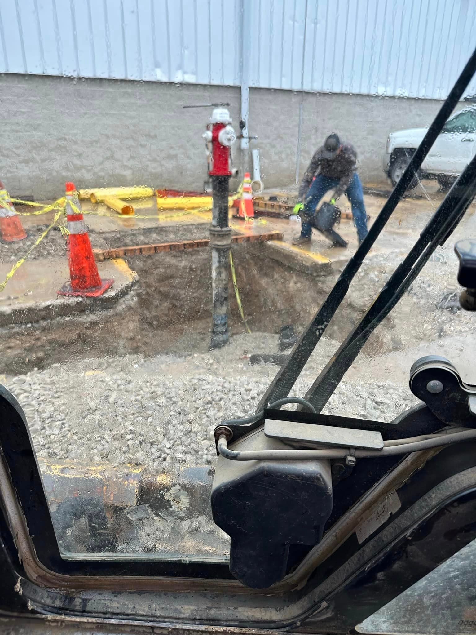 A man is standing in a hole in the ground next to a fire hydrant.