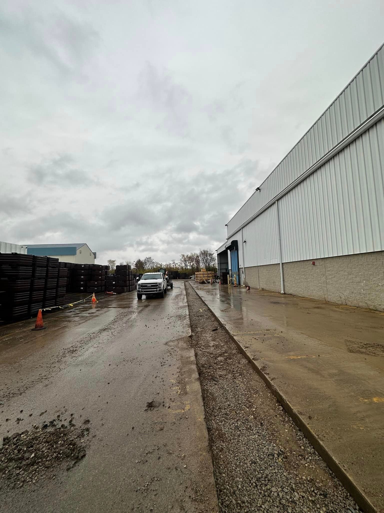 A car is driving down a wet road in front of a building.