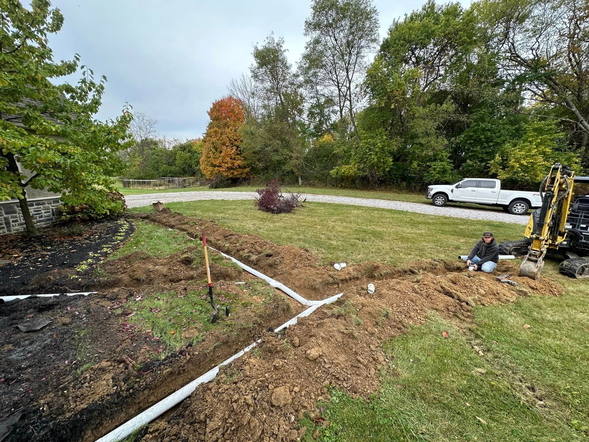 A man is laying in the dirt next to a truck.