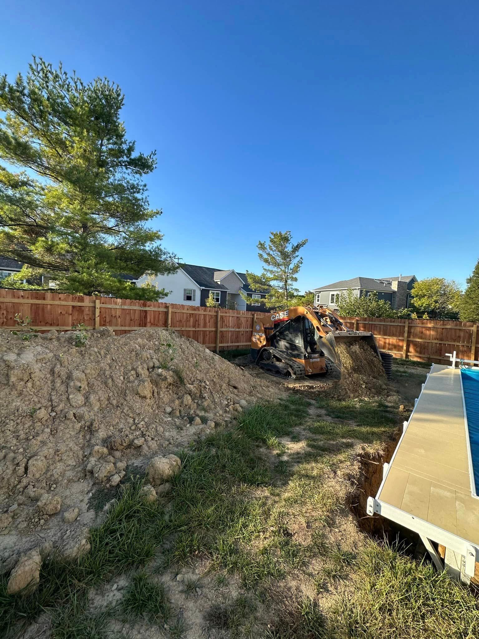 A large pile of dirt is sitting next to a pool in a backyard.