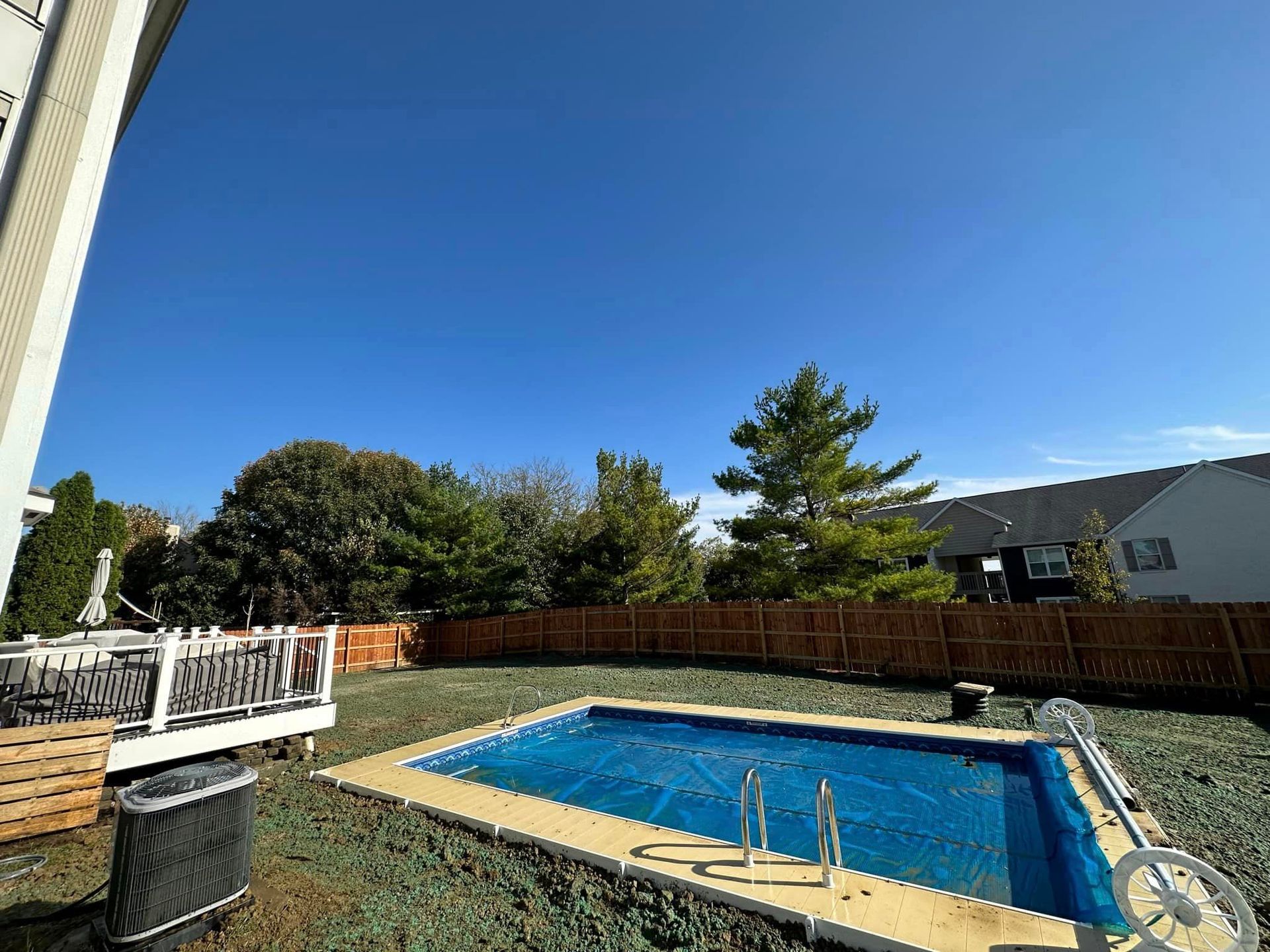 There is a large swimming pool in the backyard of a house.