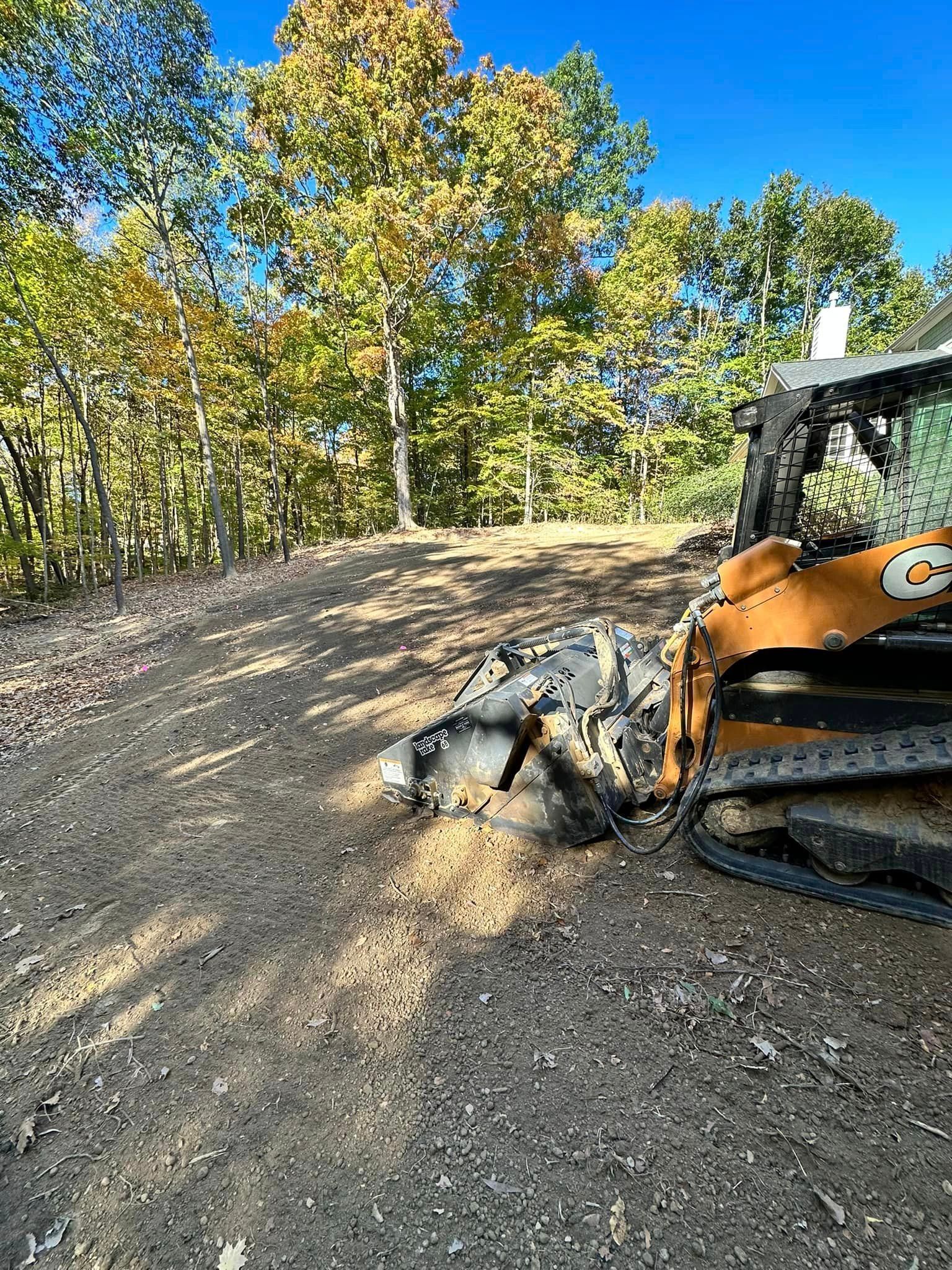 A bulldozer is sitting on top of a dirt road in the woods.