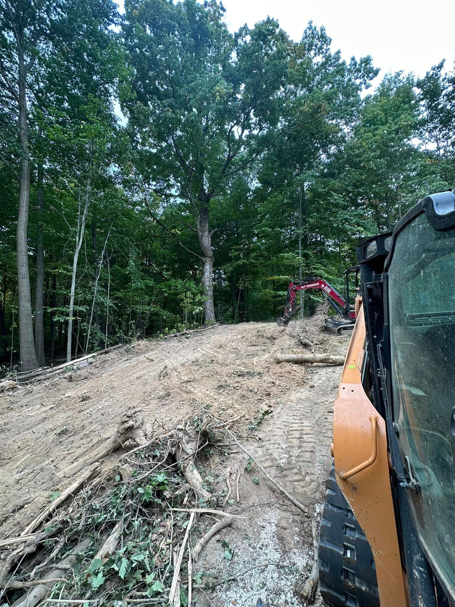 A bulldozer is driving down a dirt road in the woods.