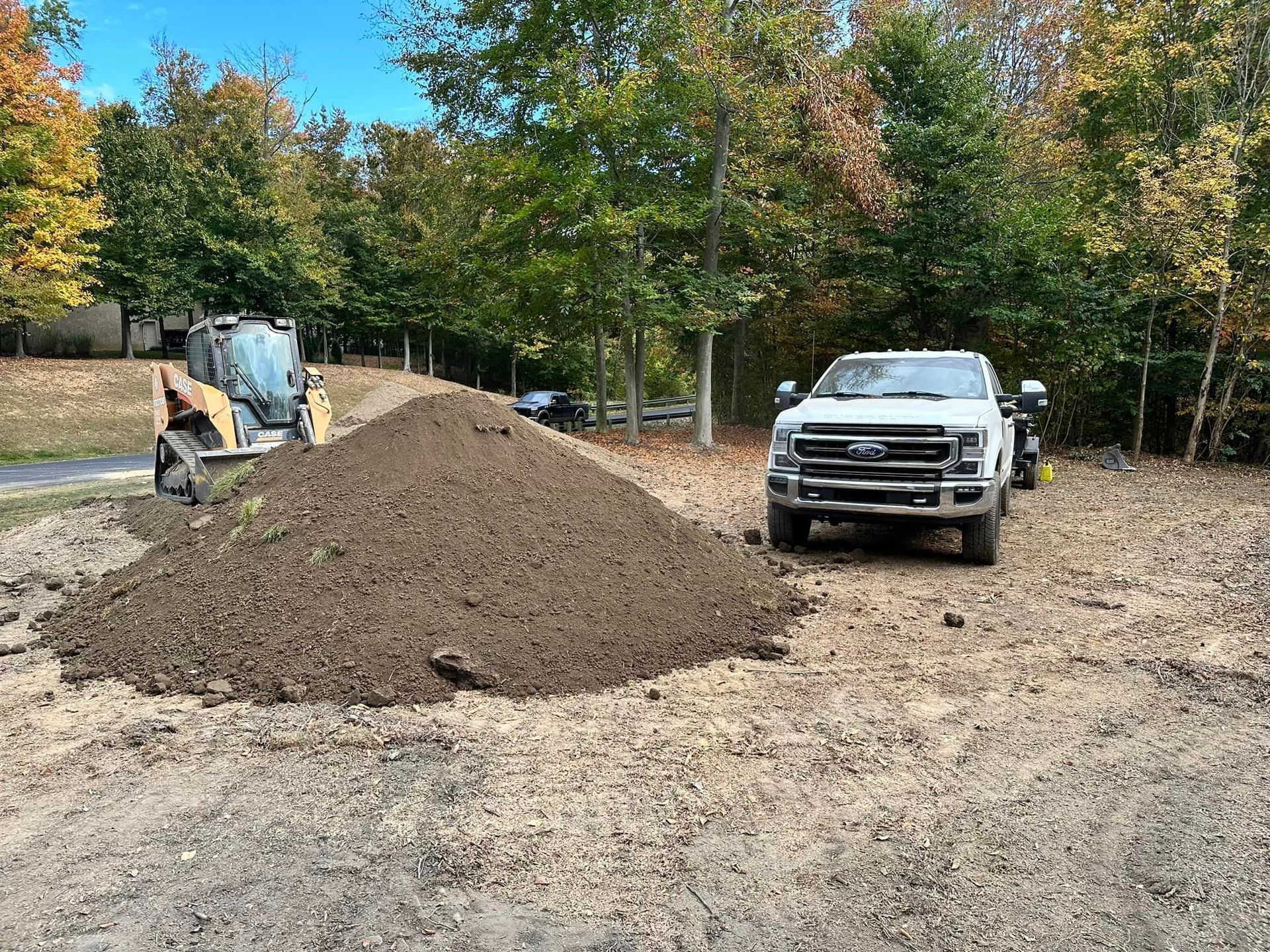 A white truck is parked next to a pile of dirt.