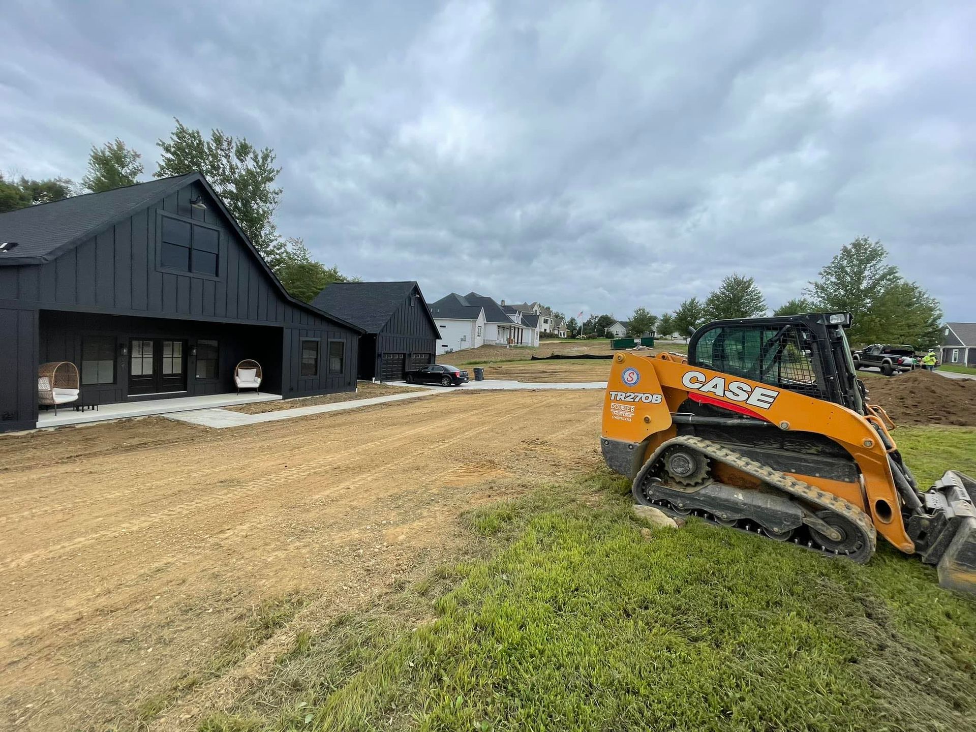 A bulldozer is sitting in a dirt field in front of a house.