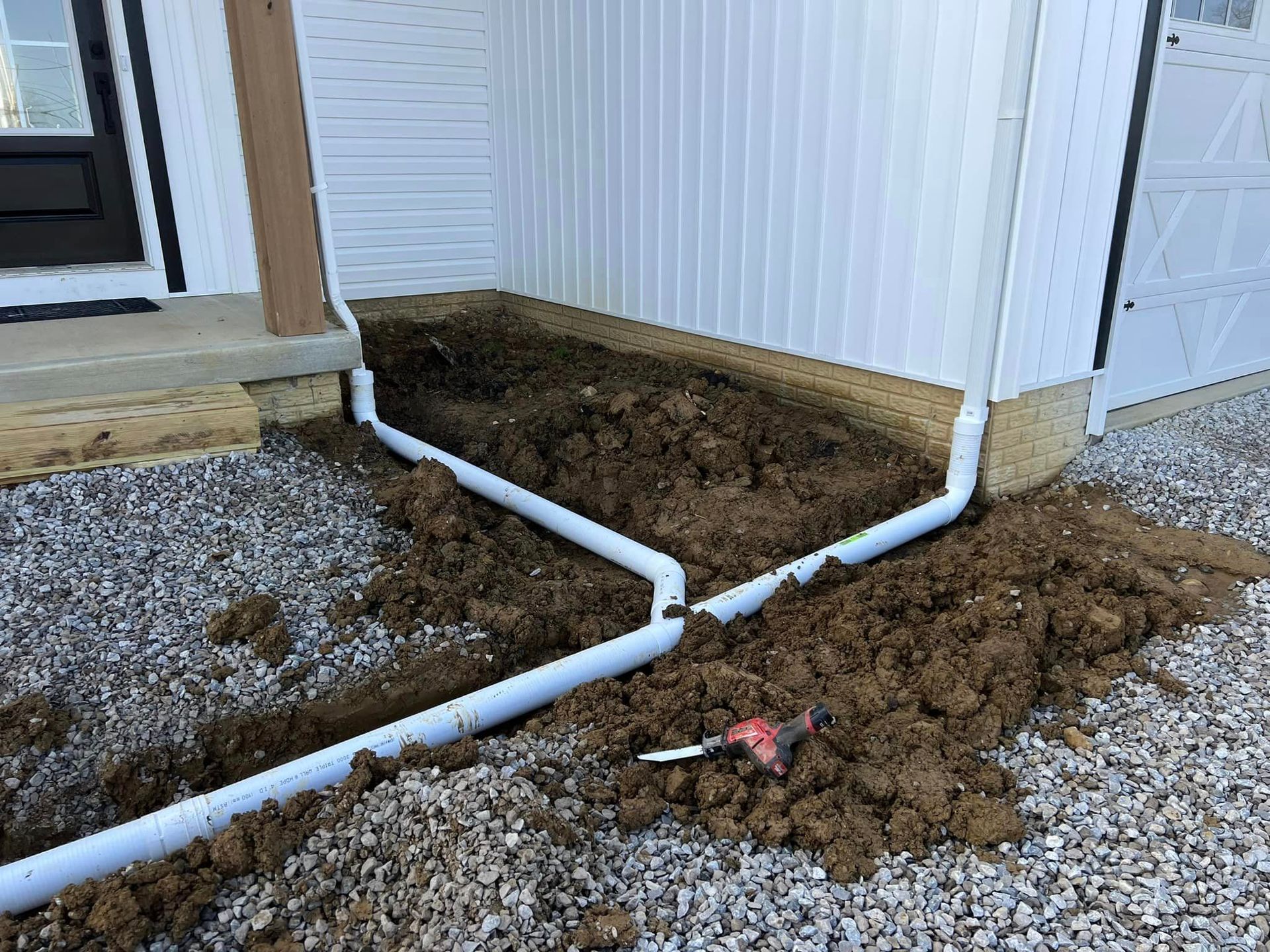 A drain pipe is being installed on the side of a house.