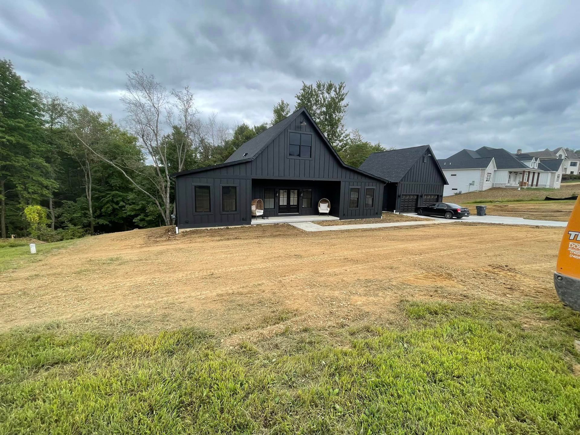 A black house is sitting in the middle of a field.