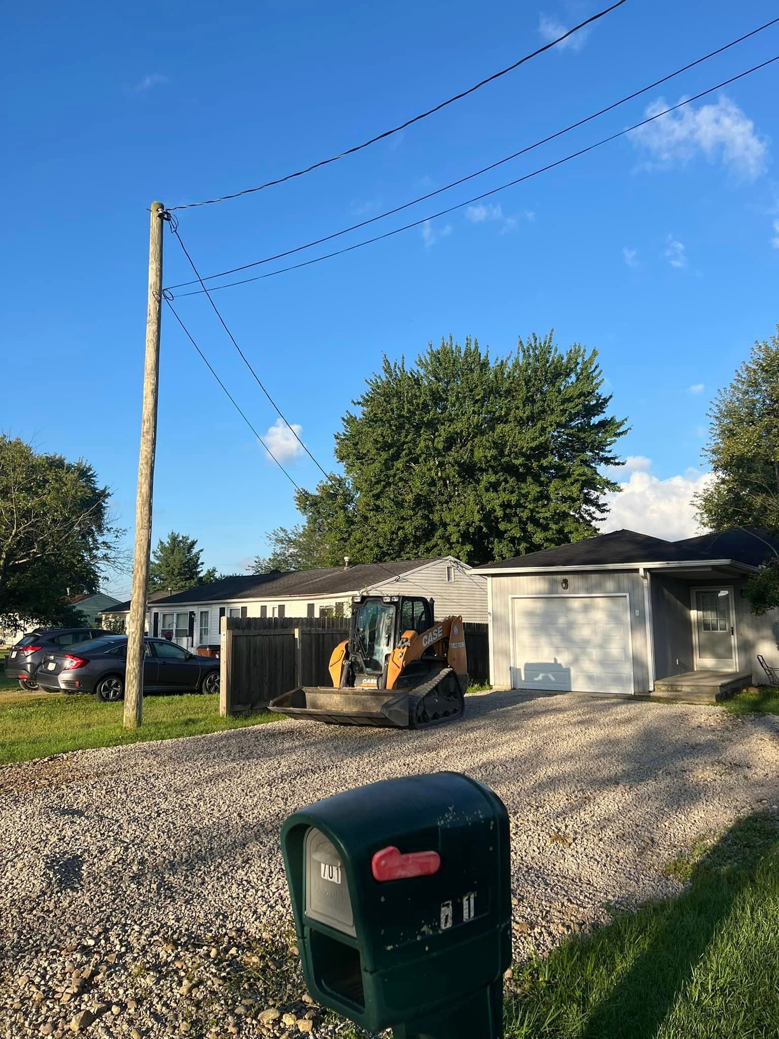 A tractor is parked in front of a house next to a mailbox.