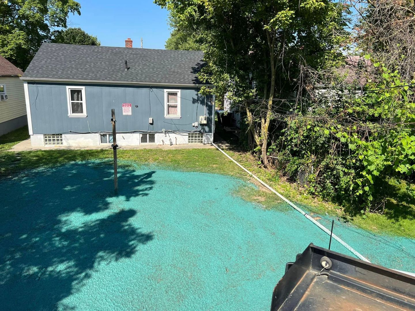 A blue house with a basketball court in front of it.