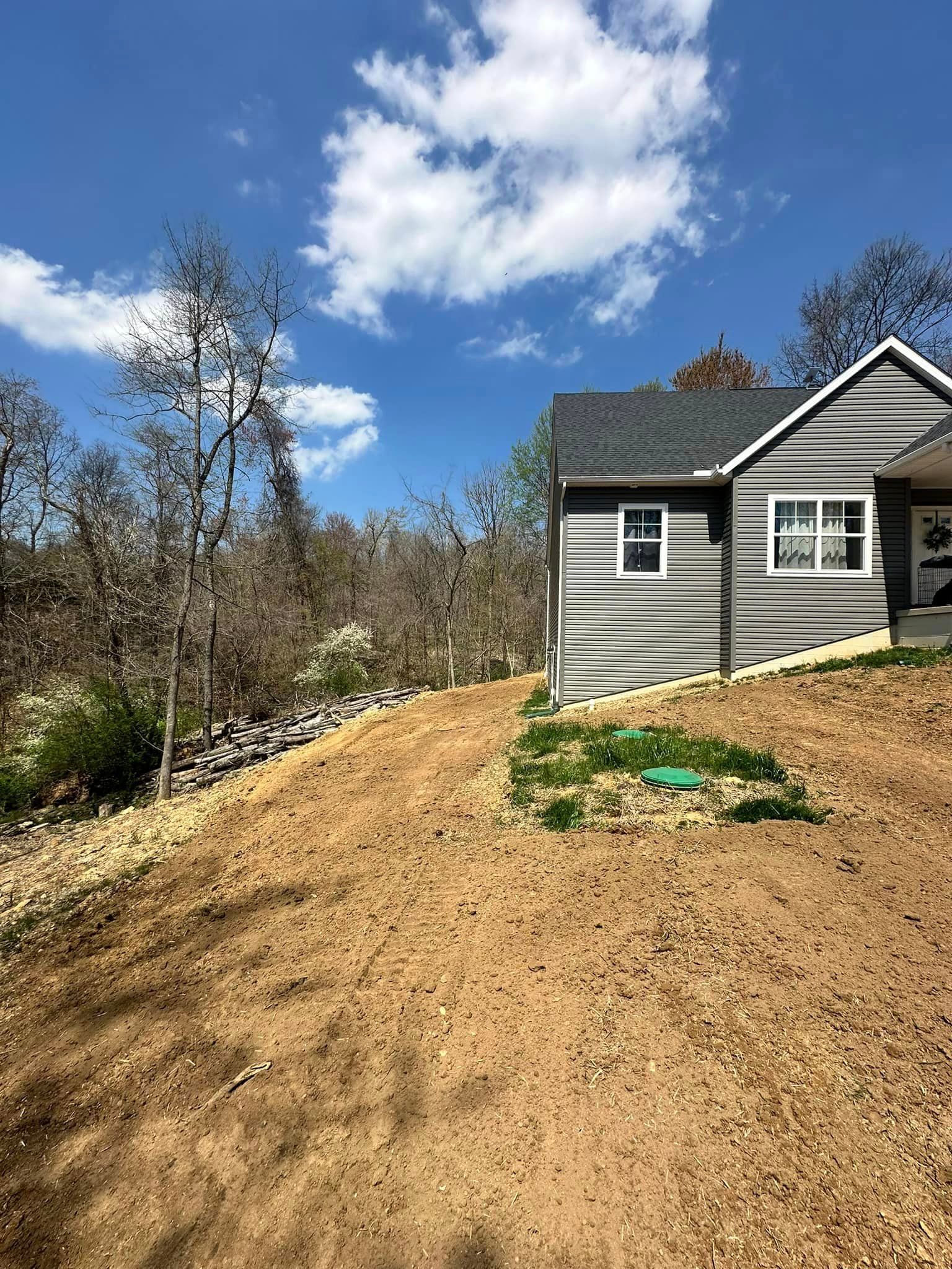 A house is sitting on top of a hill next to a dirt road.