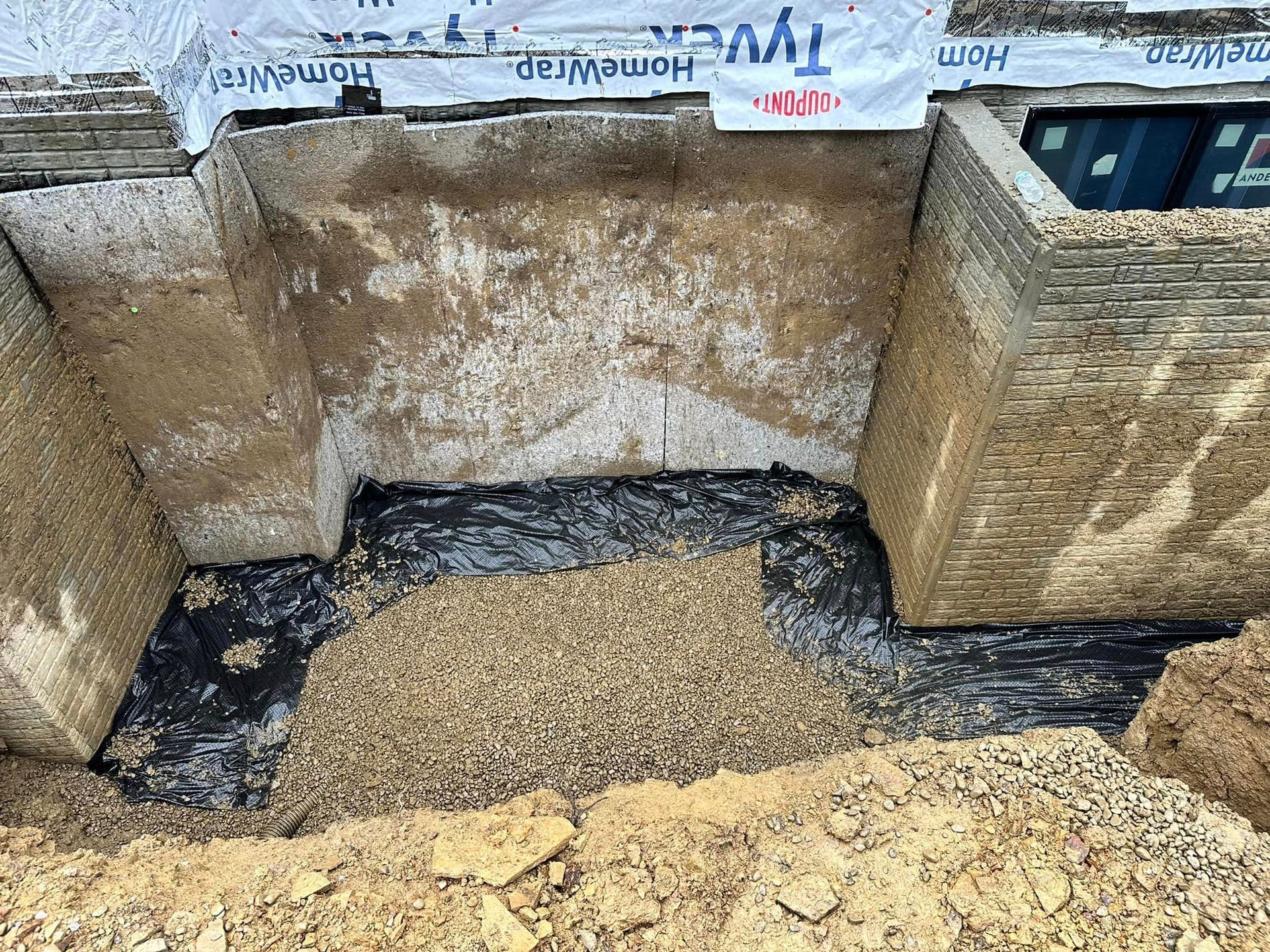 A hole in the ground with a brick wall and a pile of dirt.