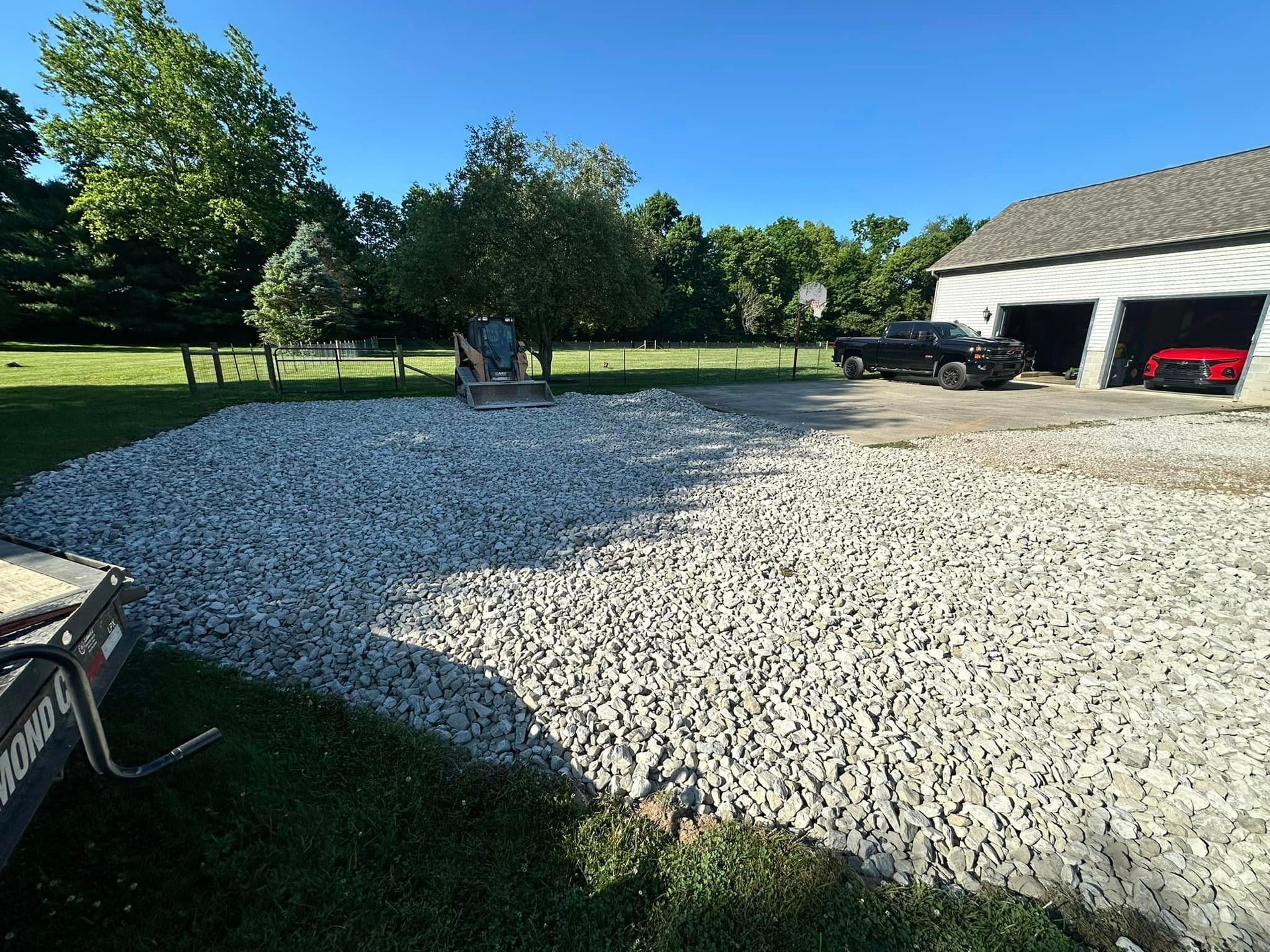 A gravel driveway in front of a garage with cars parked in it.