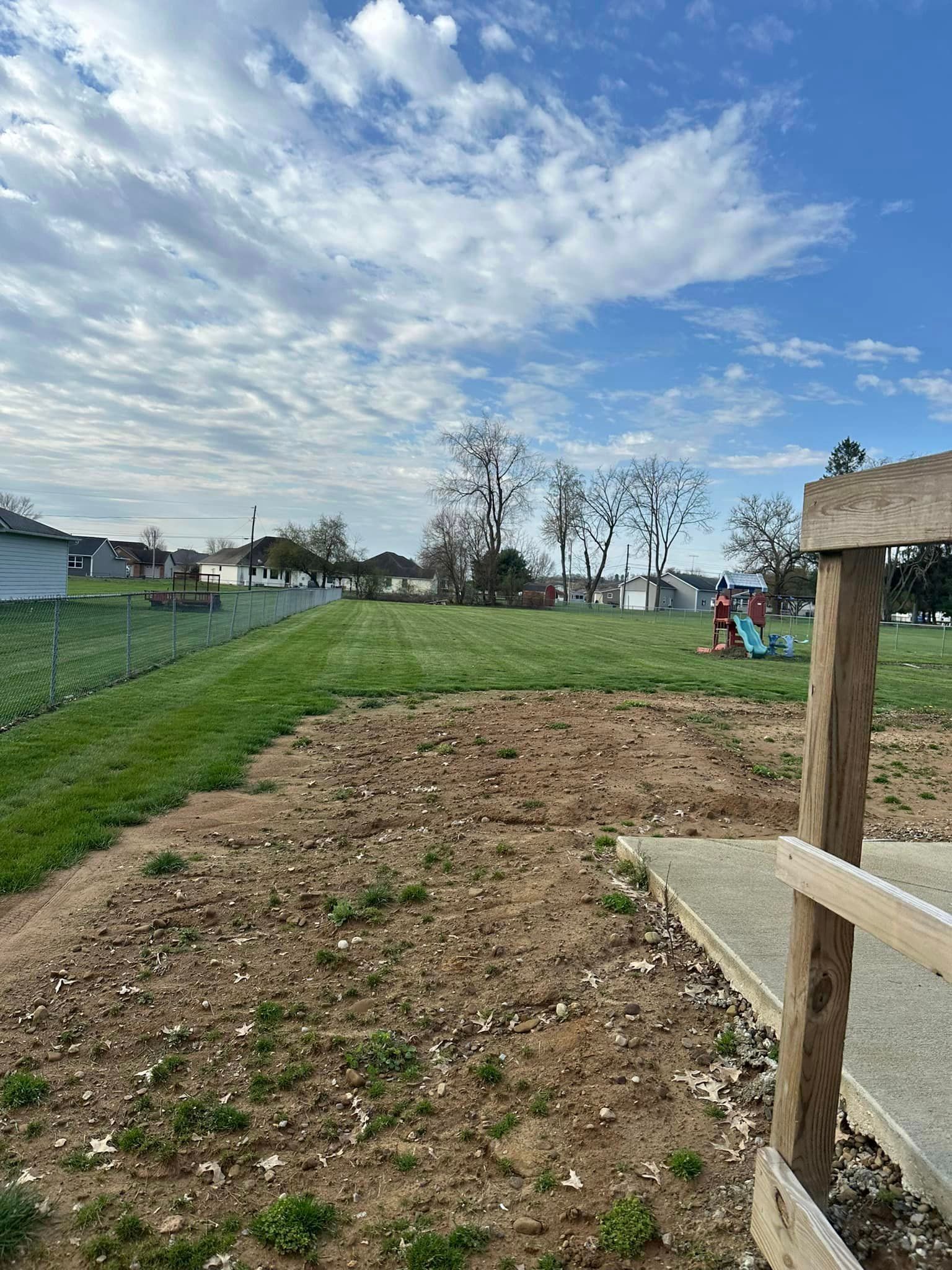 A wooden bench is sitting in the middle of a grassy field.