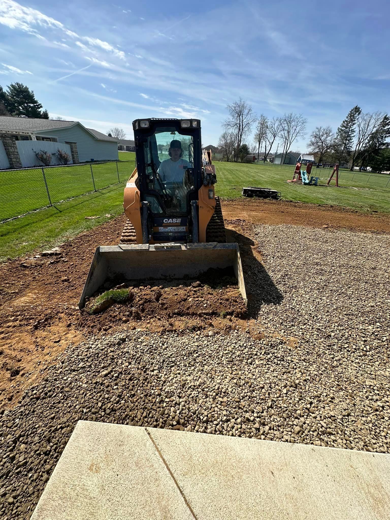 A man is driving a bulldozer on a gravel road.