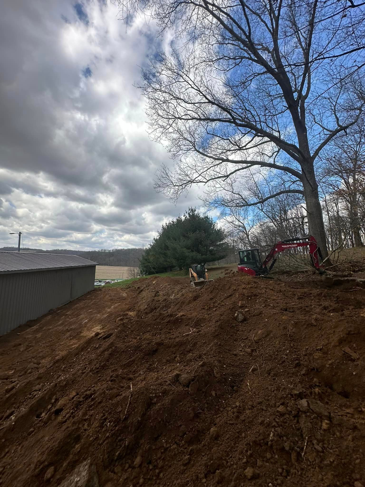 A large pile of dirt with a tree in the background.