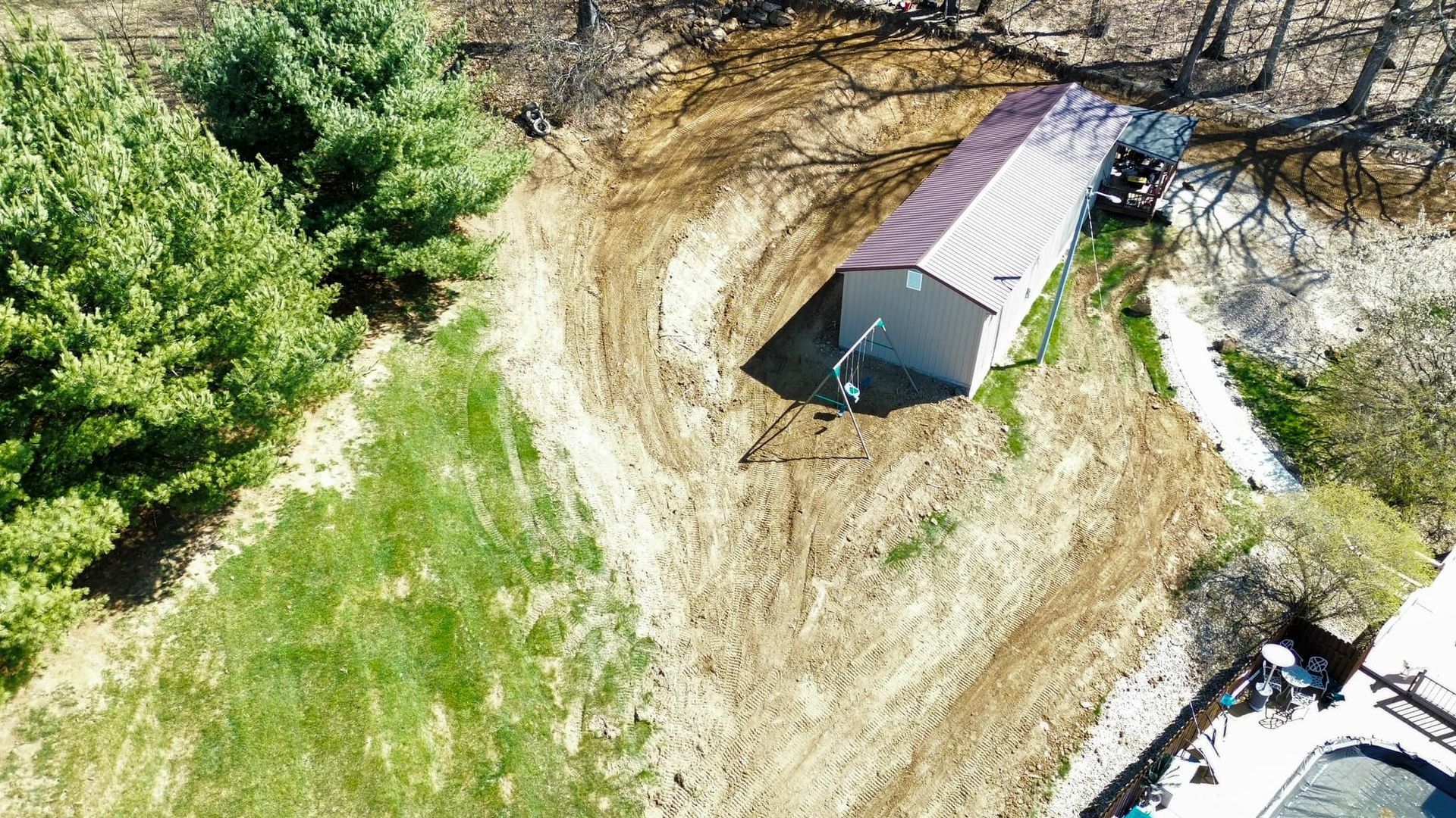 An aerial view of a shed in the middle of a dirt field.