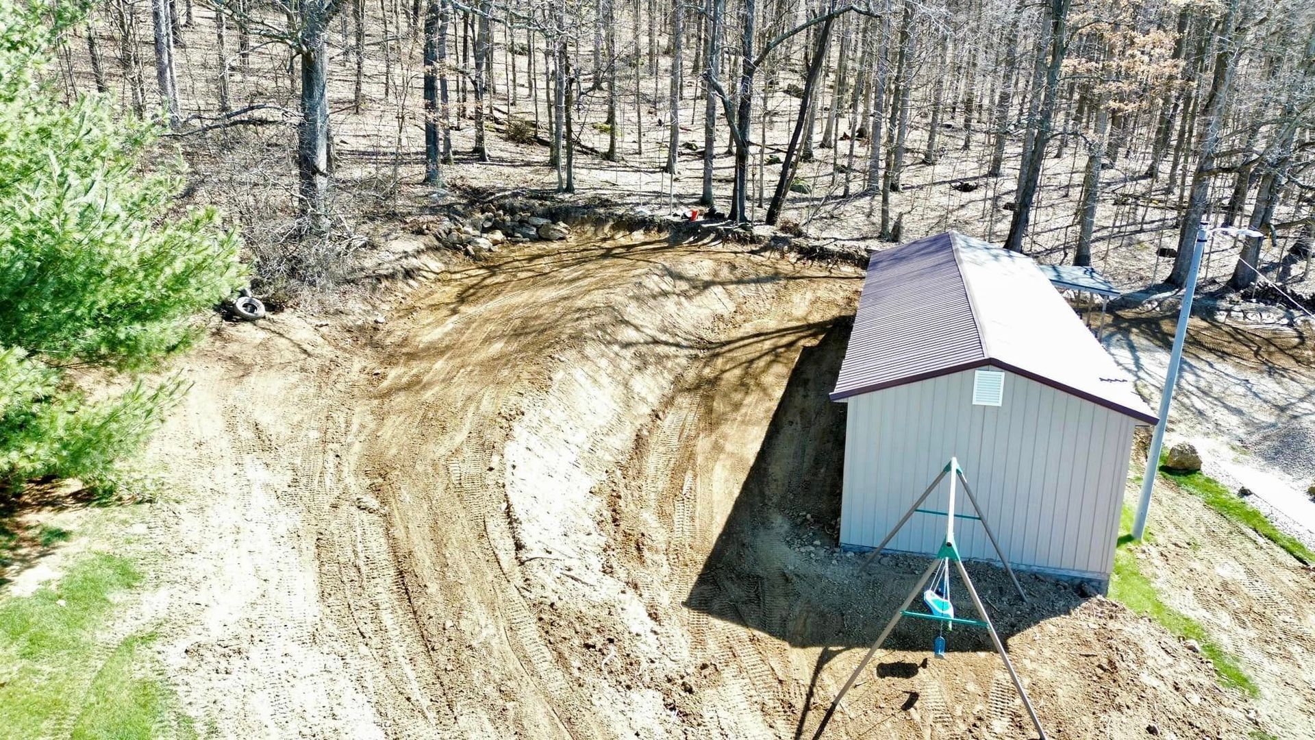 An aerial view of a small shed in the middle of a dirt field.