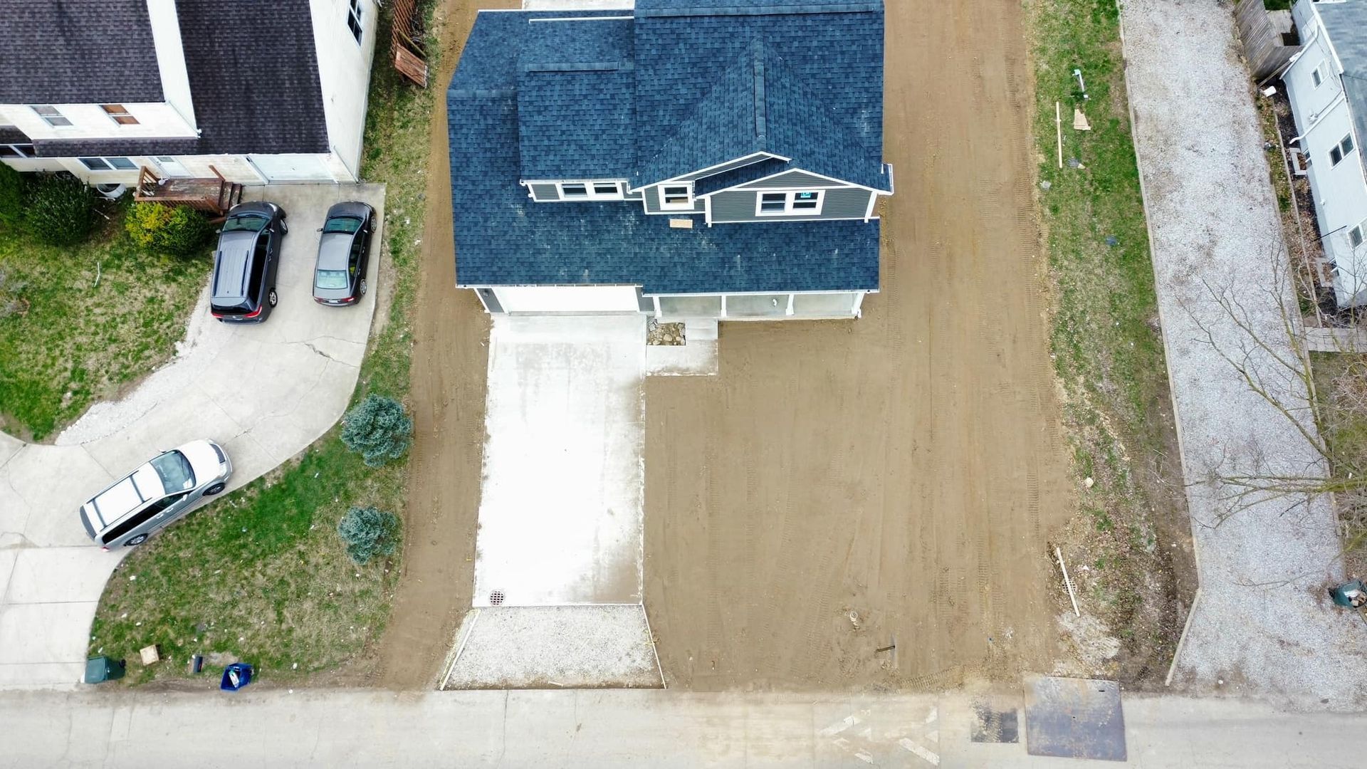 An aerial view of a house and driveway with cars parked in front of it.