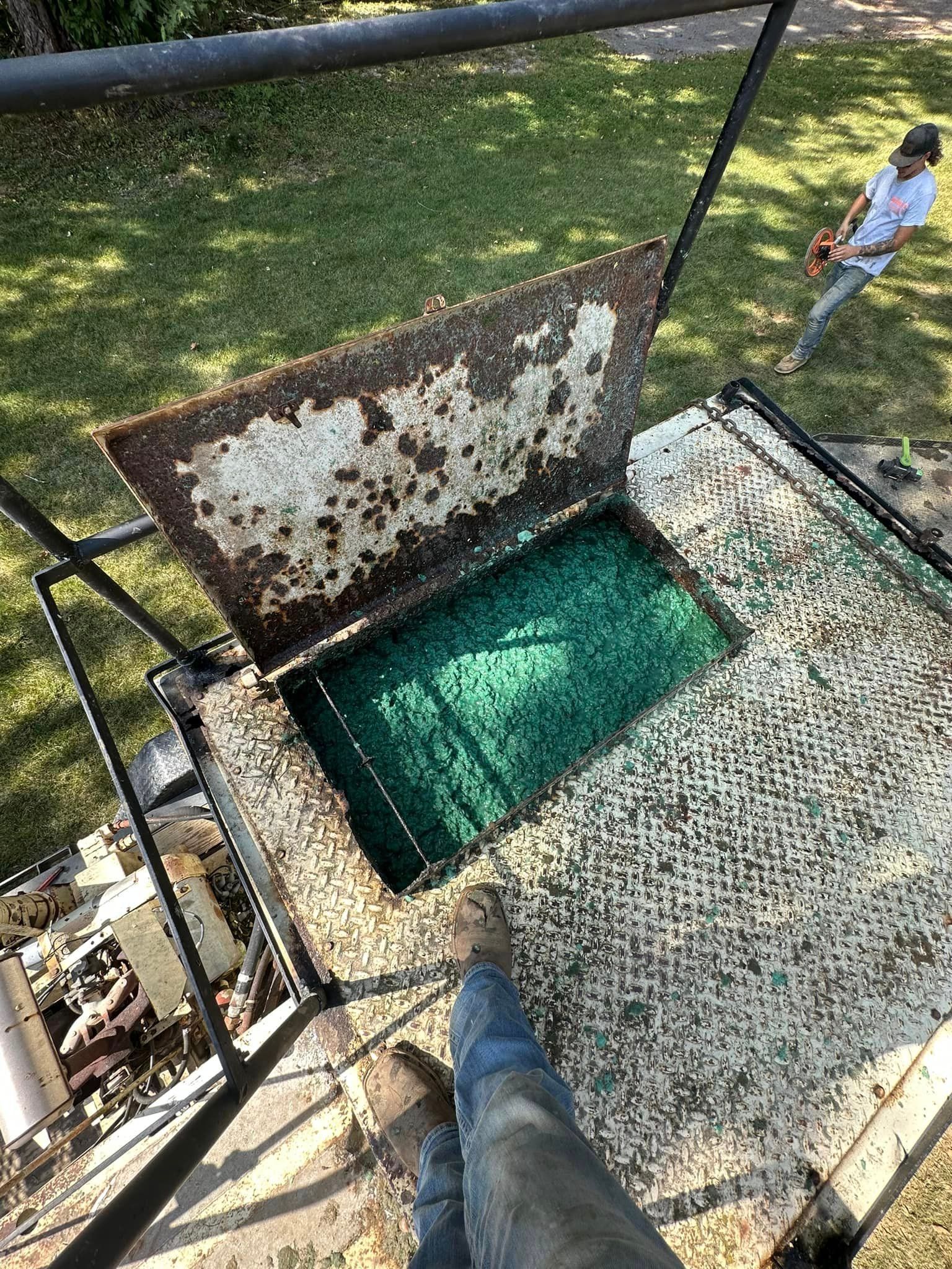 A person is standing on top of a metal platform next to a manhole cover.