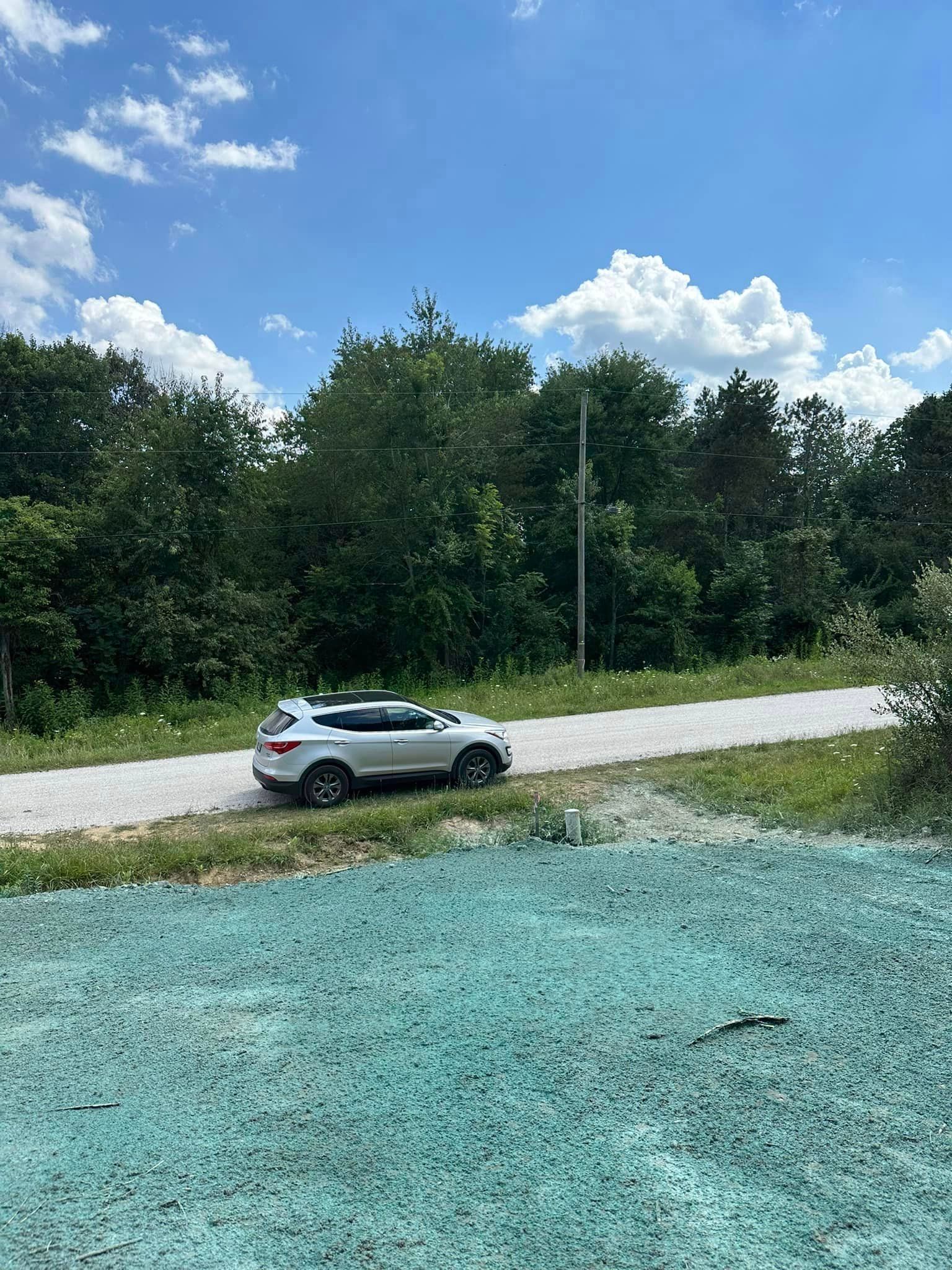 A white suv is parked on the side of a dirt road.