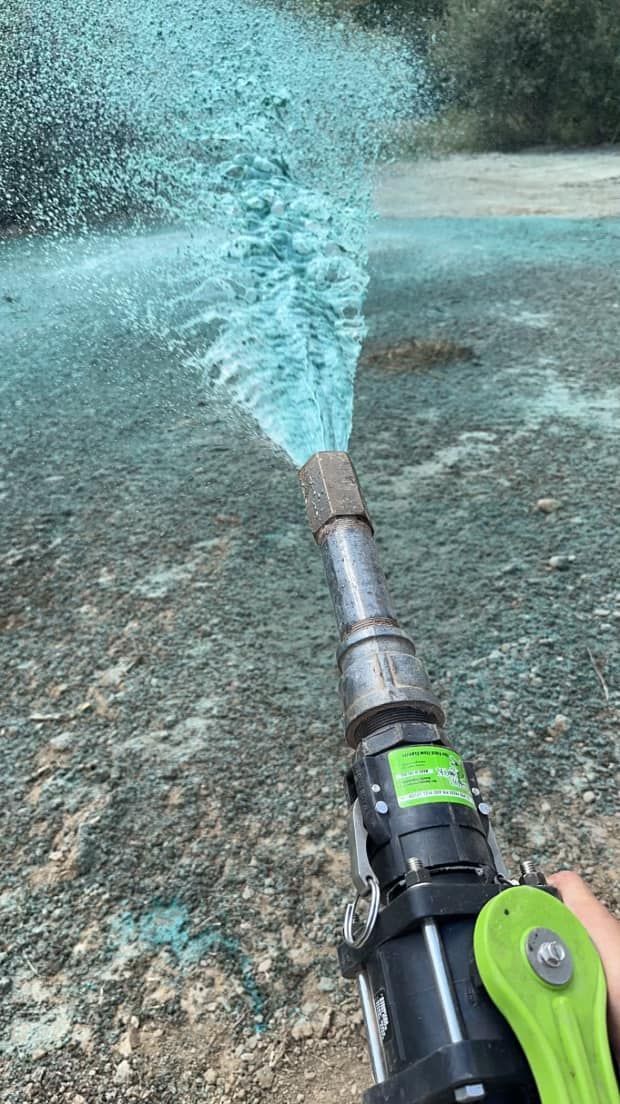 A person is holding a hose that is spraying blue liquid.