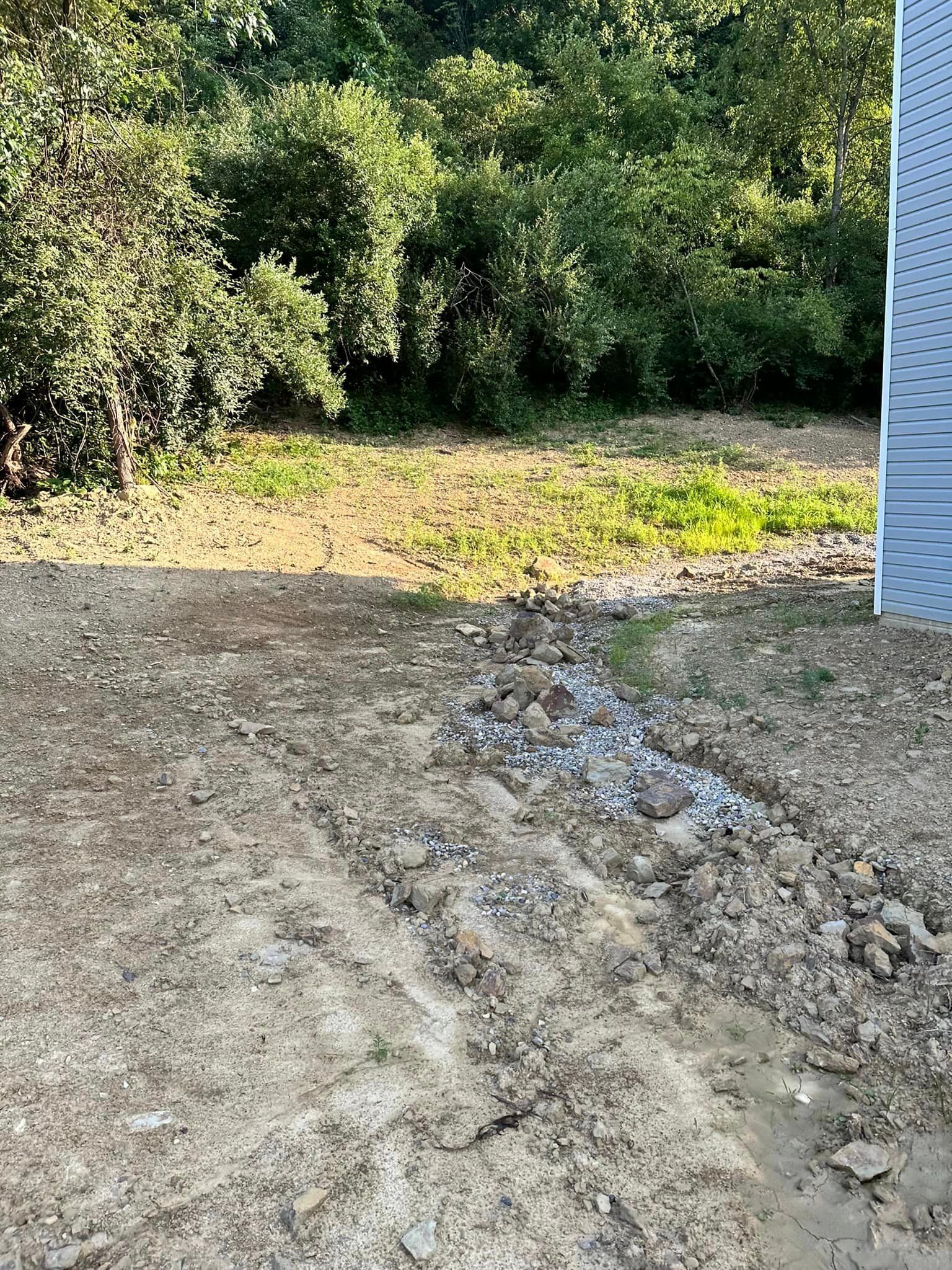 A dirt road leading to a house with trees in the background.