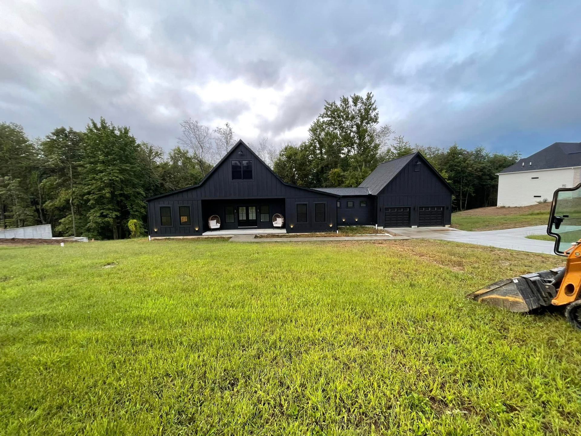 A black house is sitting in the middle of a lush green field.