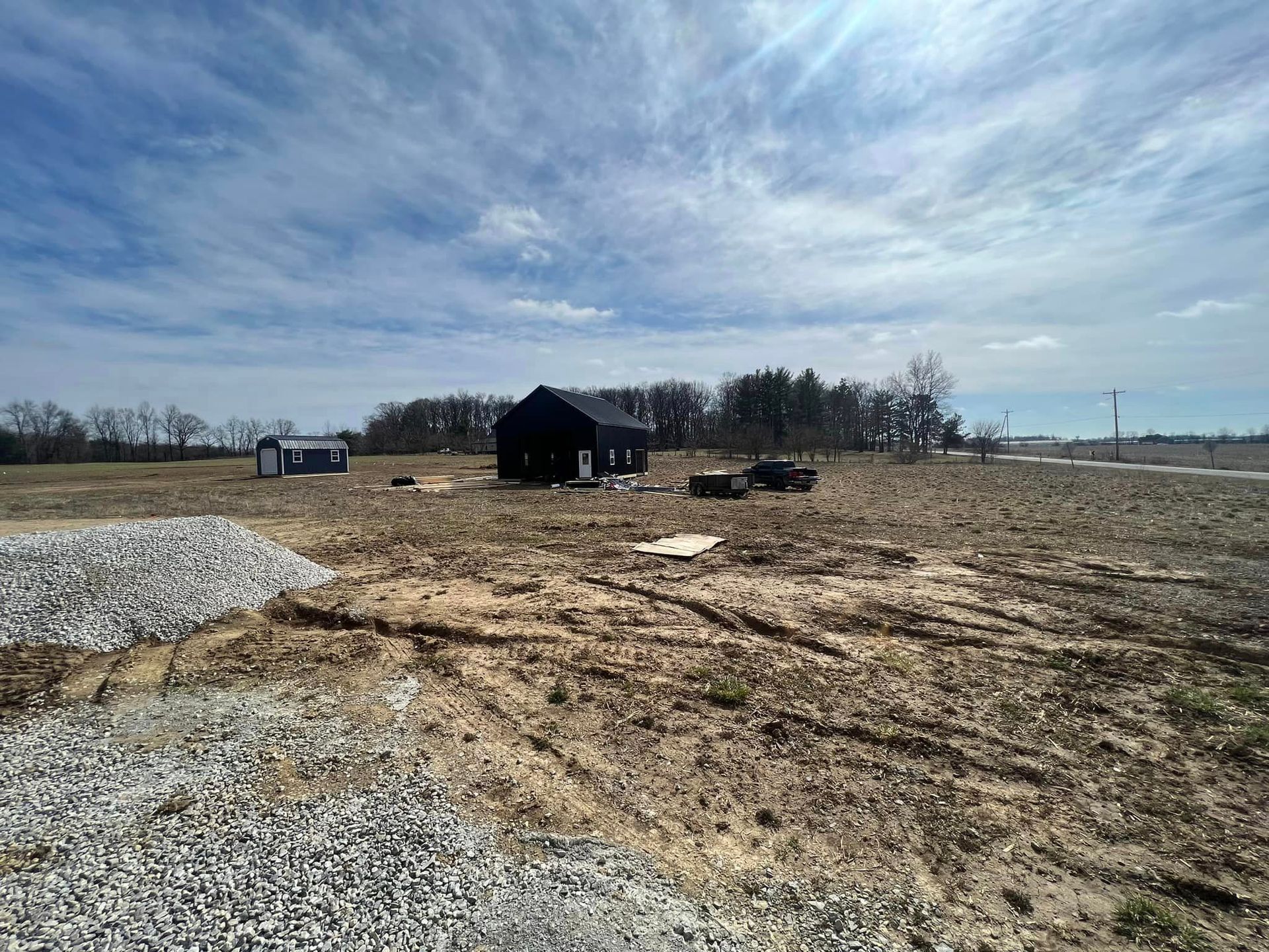 A large dirt field with a house in the background.