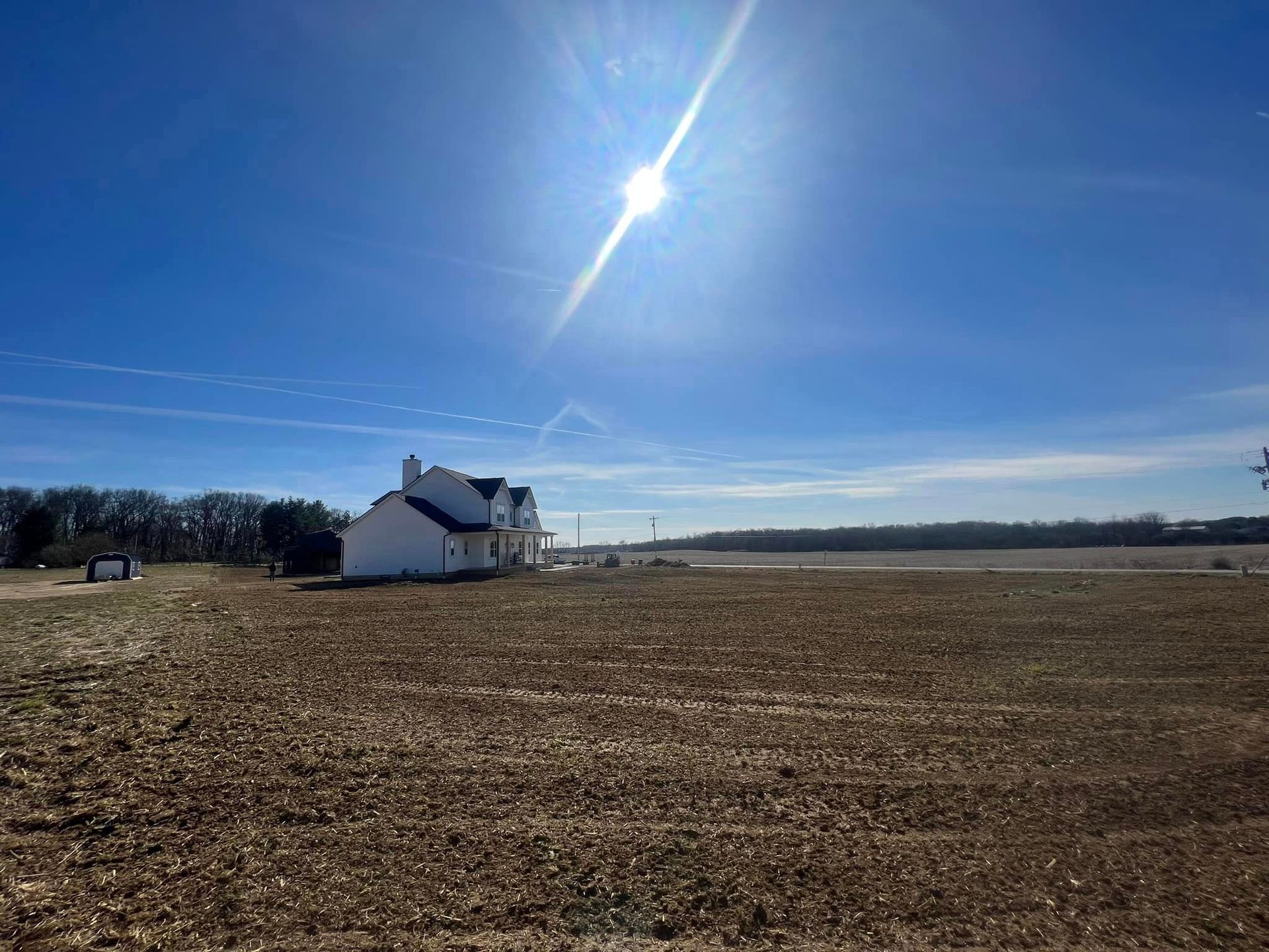 A white house is sitting in the middle of a field.