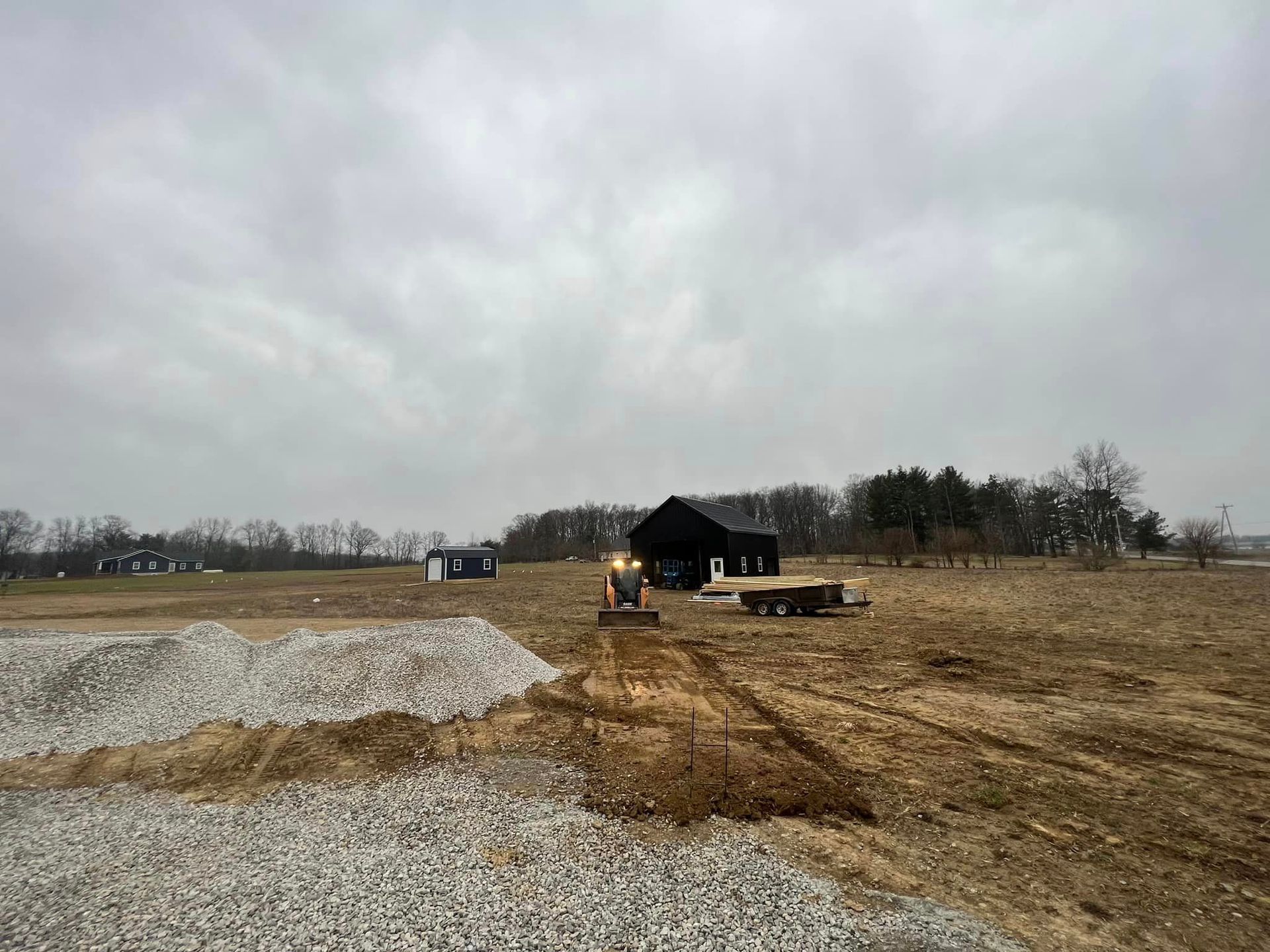 A large dirt field with a house in the background and a bulldozer in the foreground.