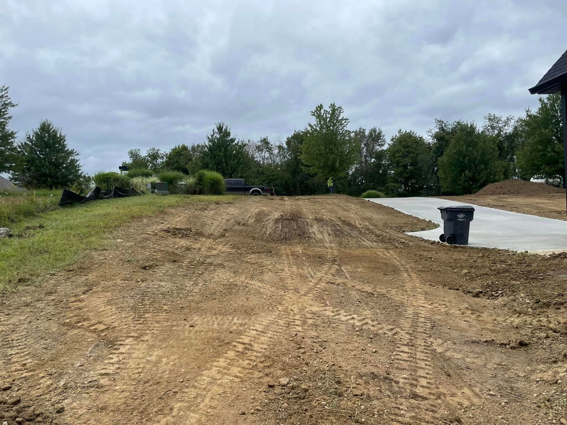 A dirt road with a trash can in the middle of it.