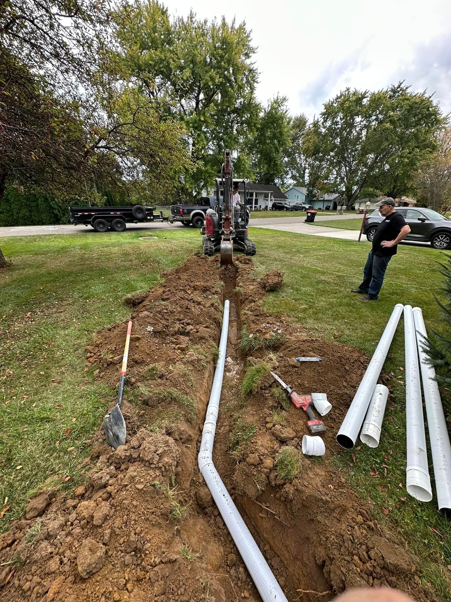 A man is standing in the dirt next to a pile of pipes.