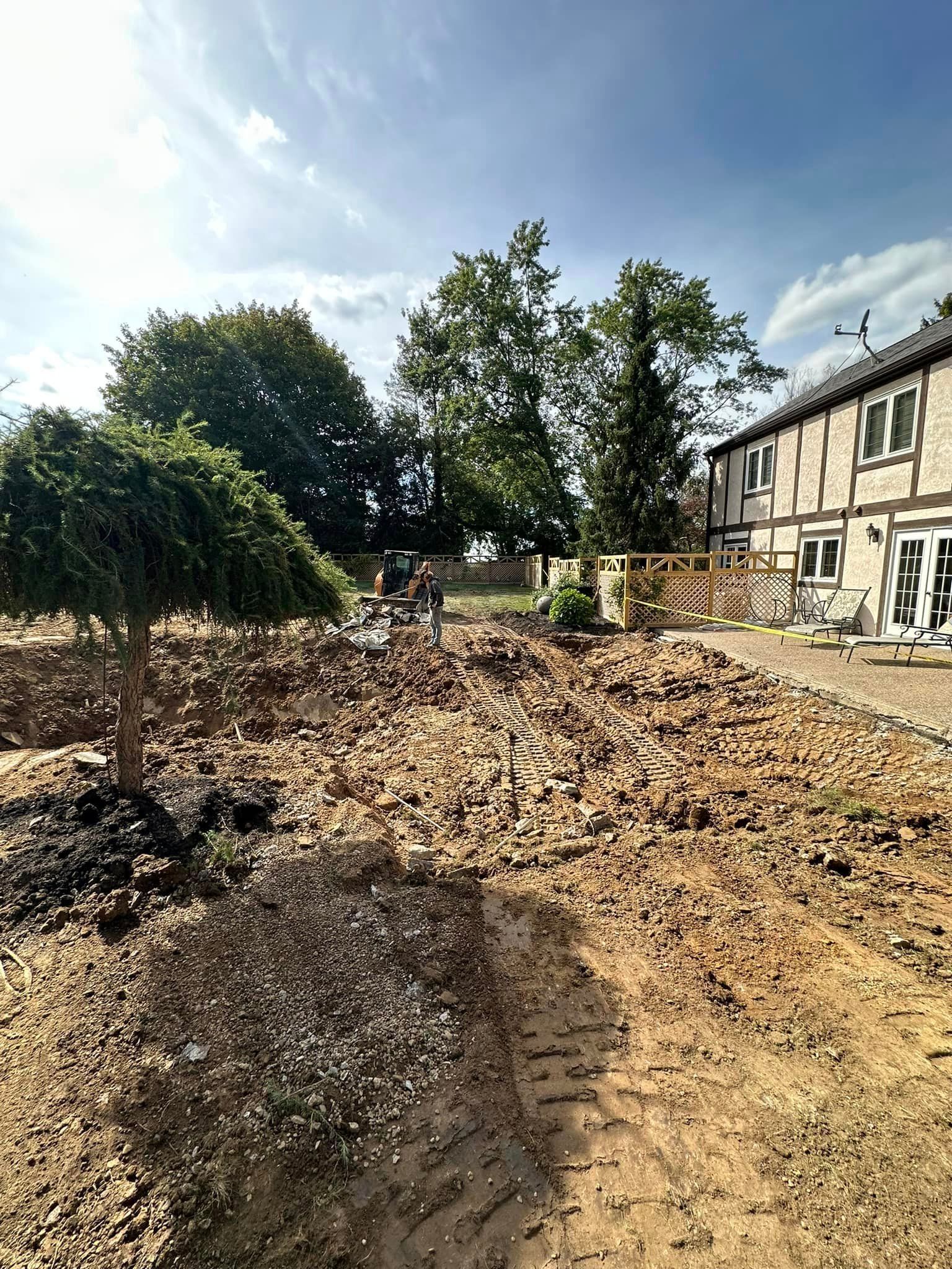 A dirt road leading to a house with trees in the background.