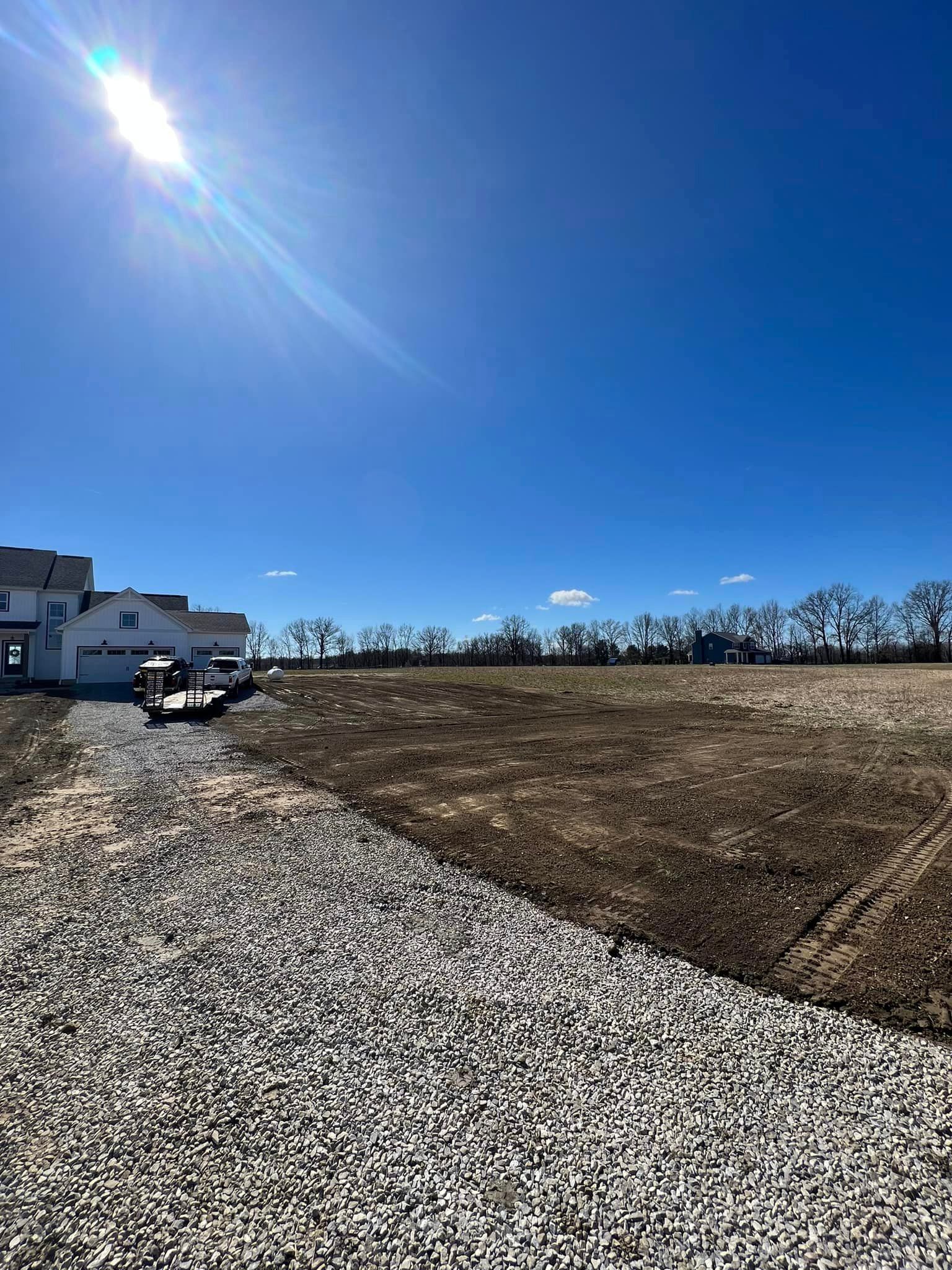 A gravel driveway leading to a house on a sunny day.