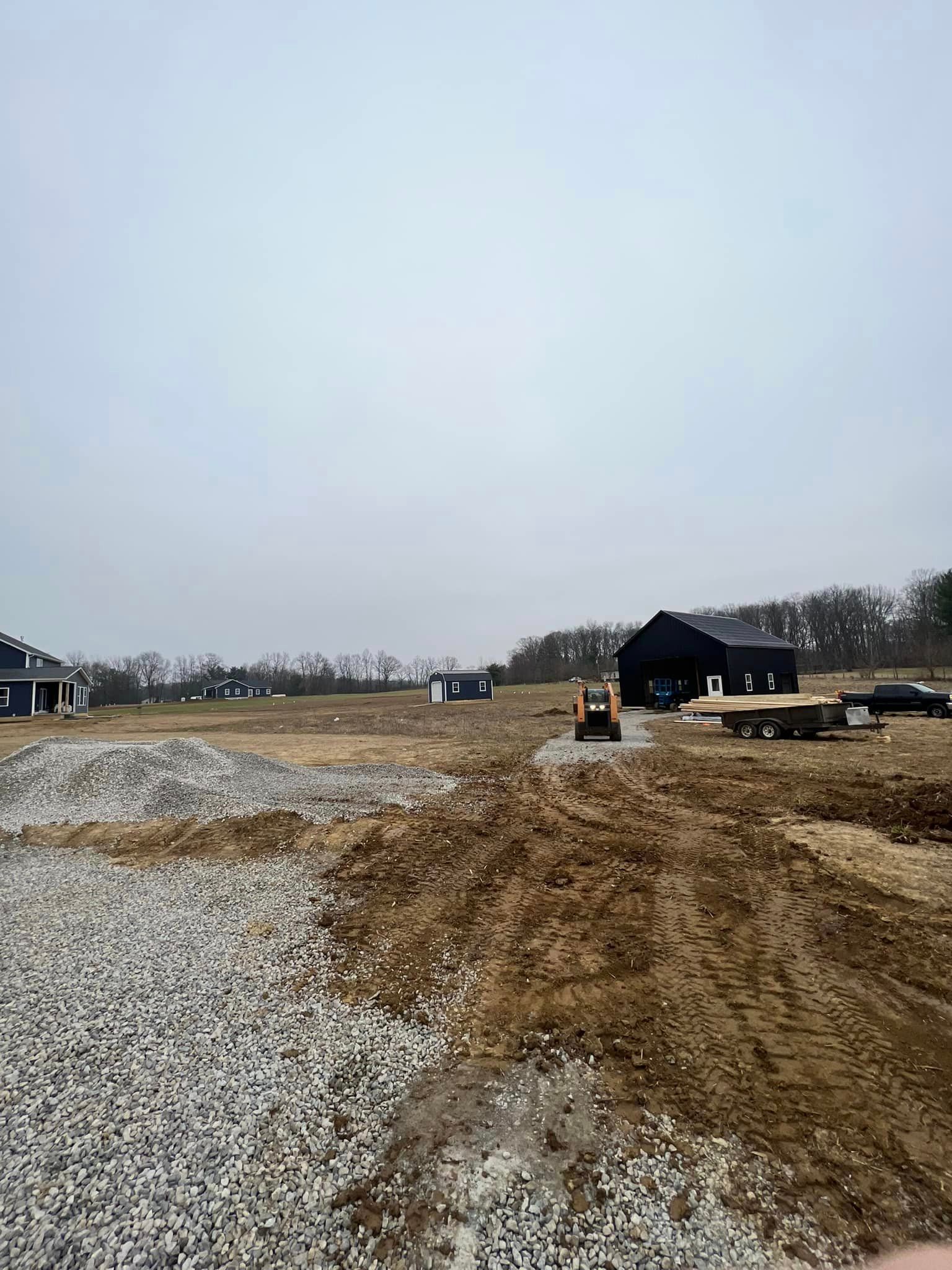 A person is standing in a dirt field with a bulldozer in the background.