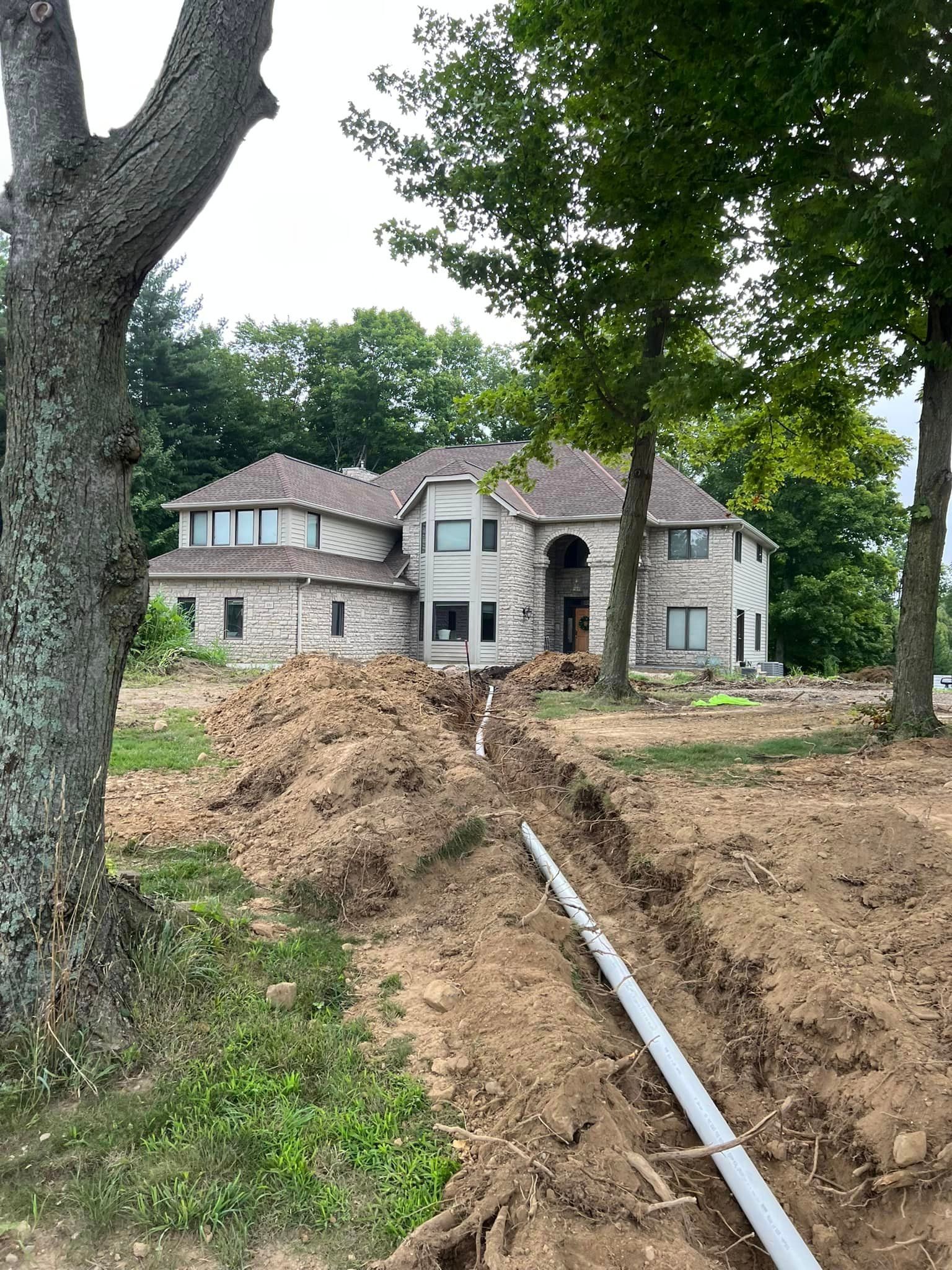 A large house is being built in the middle of a dirt field.