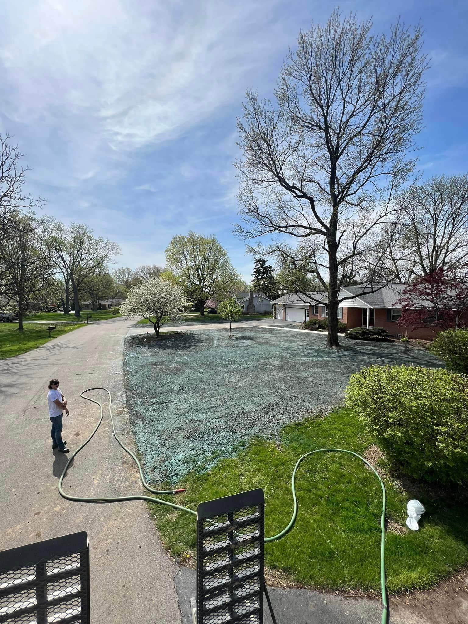 A boy is watering a lawn with a hose in front of a house.