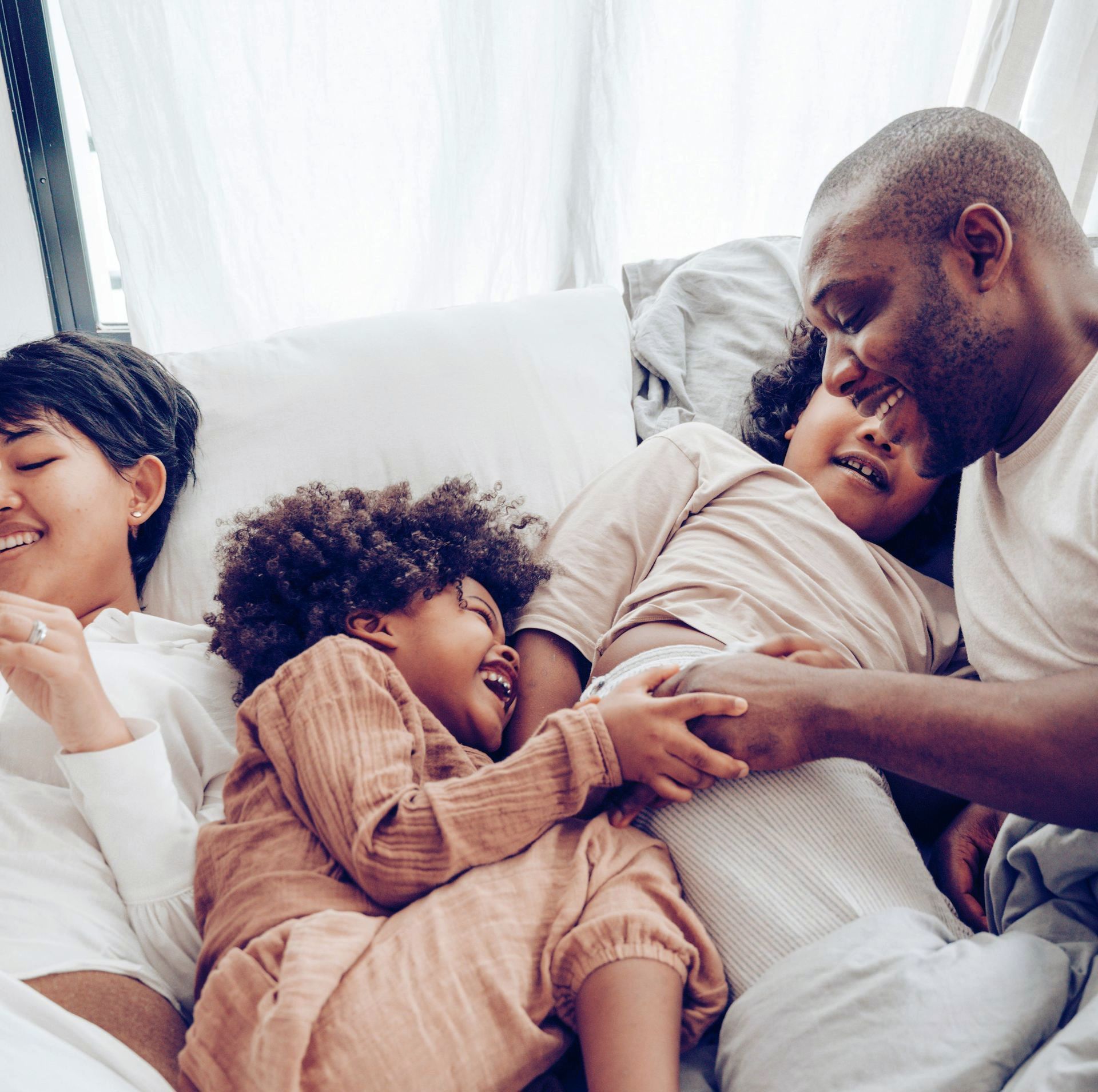 A family is laying in bed together and laughing.