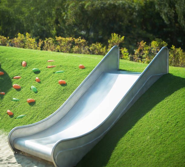 A slide is sitting on top of a grassy hill
