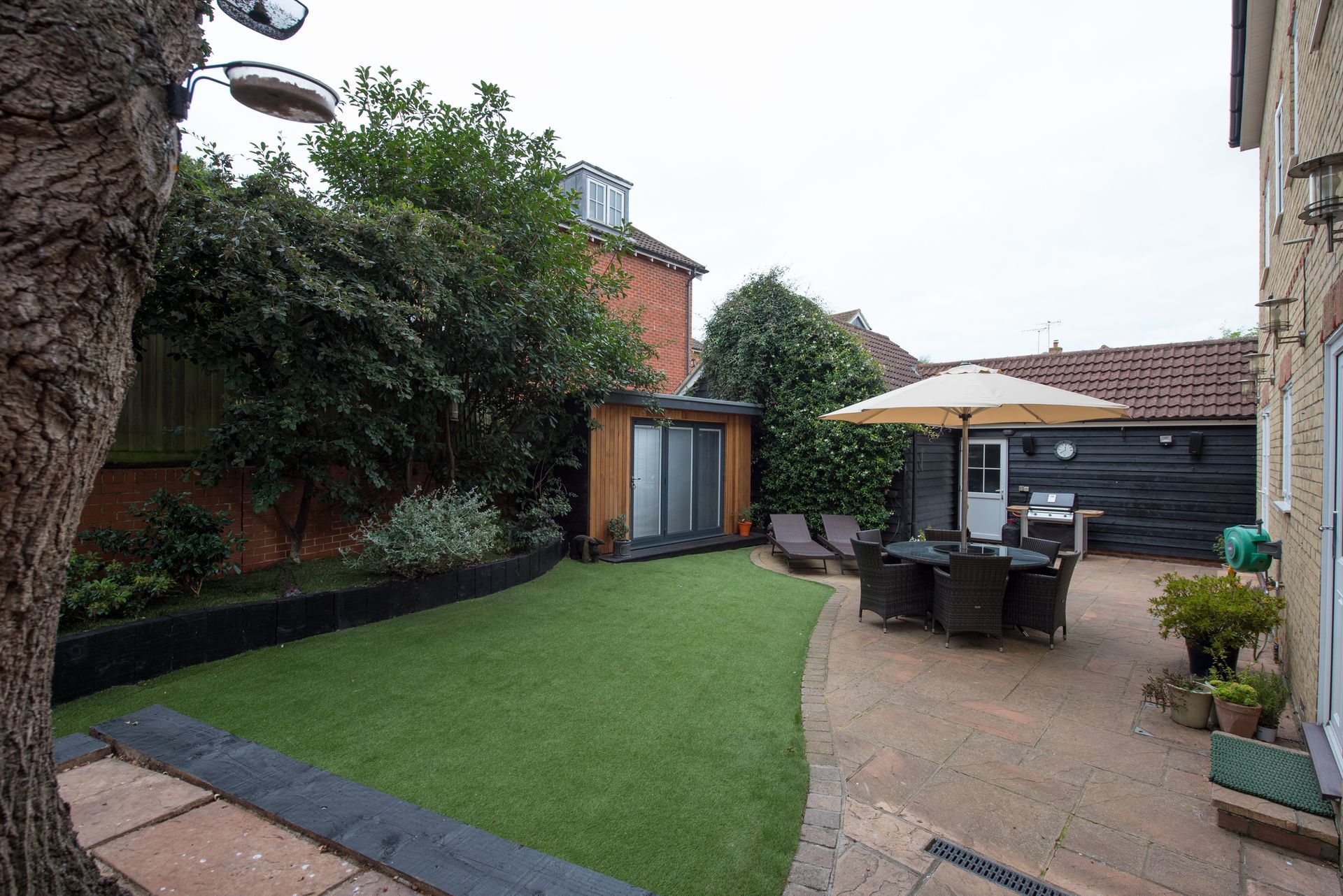 A backyard with a table and chairs under an umbrella.