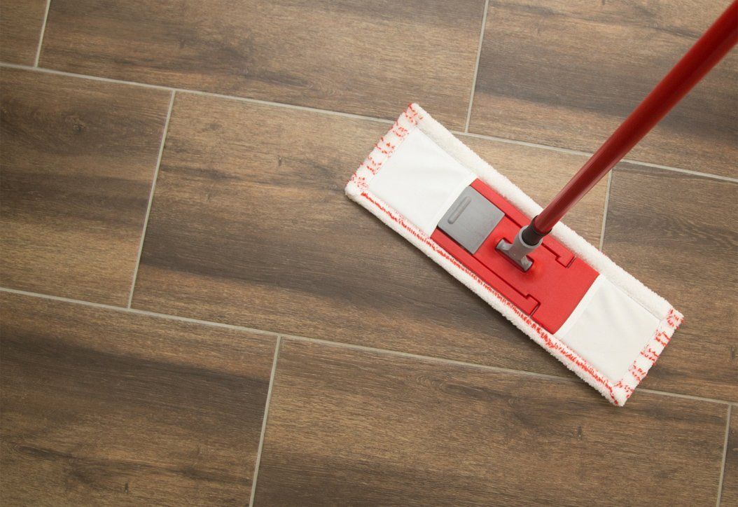 A mop cleaning a wood-textured office floor