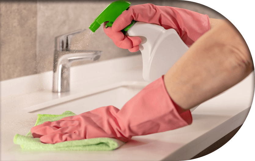 A professional cleaner disinfecting bathroom surfaces
