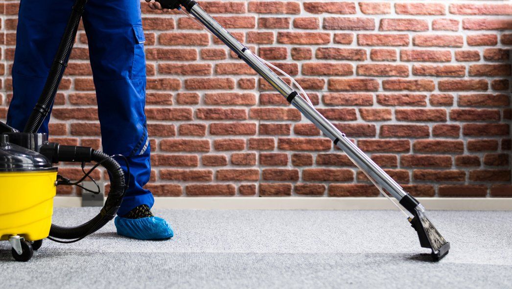 A professional cleaner vacuuming a carpeted commercial space