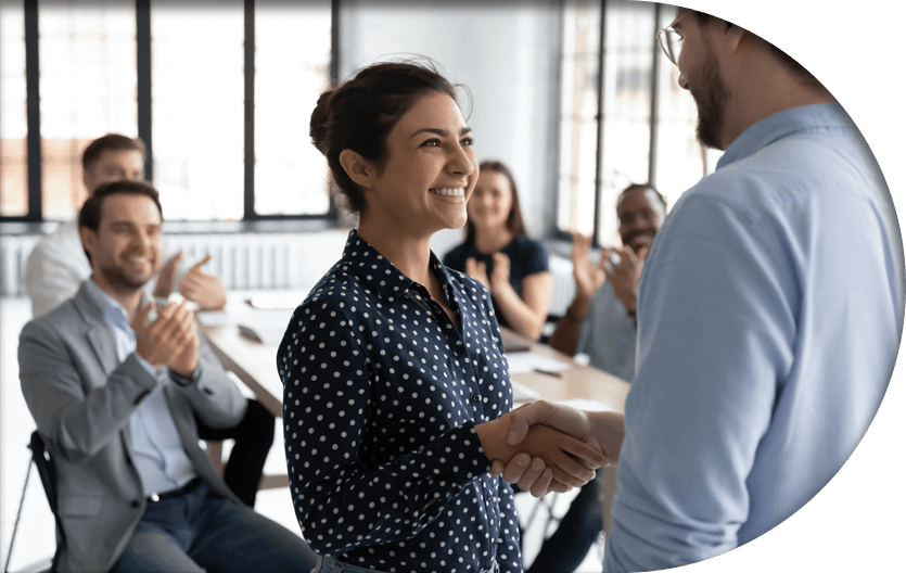 An employee and boss shaking hands while smiling