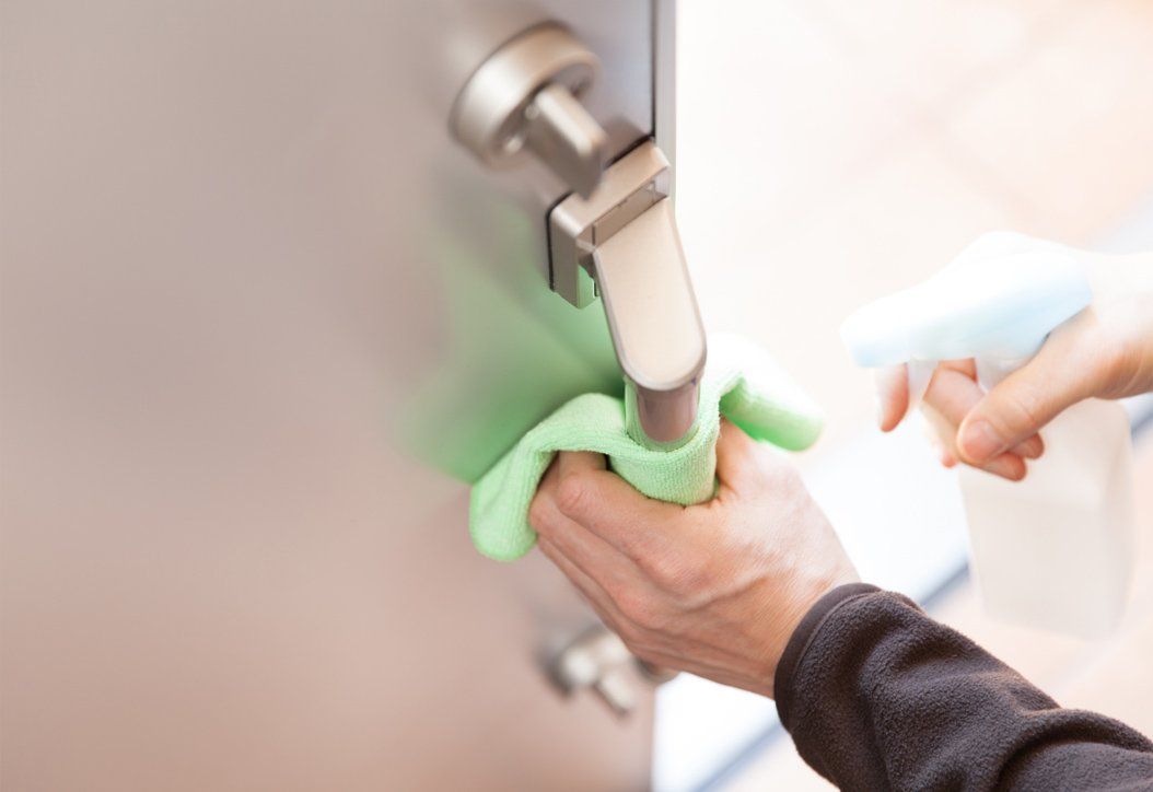 An office door knob being disinfected and wiped