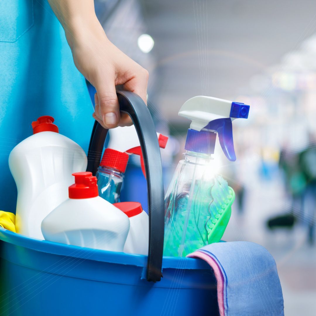 A person carries a bucket of cleaning supplies