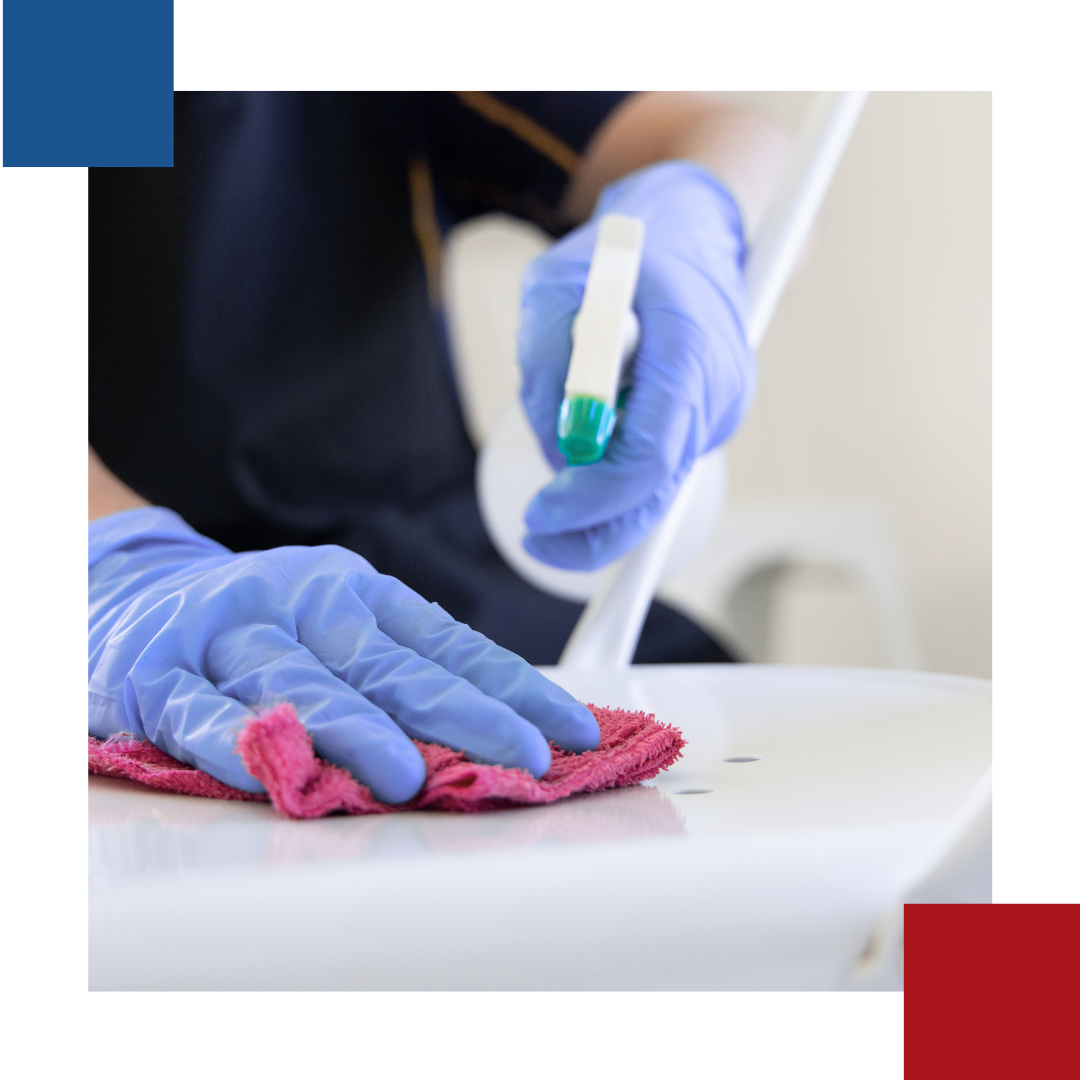 A person wearing blue gloves is cleaning a table with a cloth.