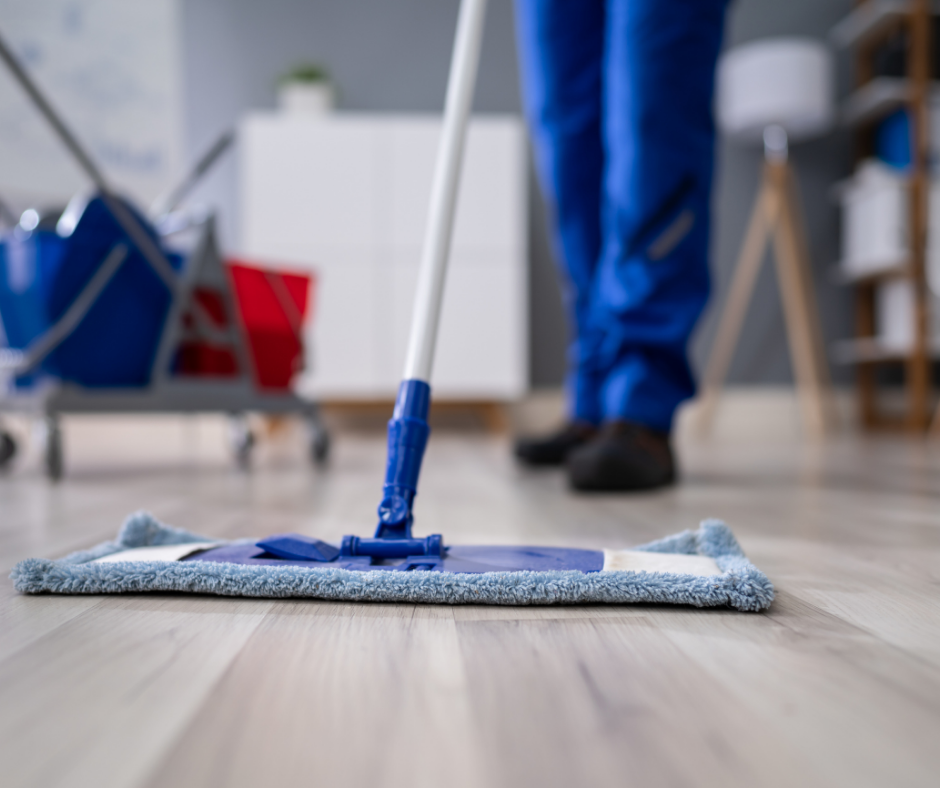 A janitor dry mopping a hardwood floor