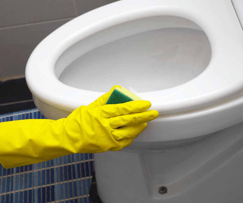 Cleaning toilet with yellow gloves and sponge.
